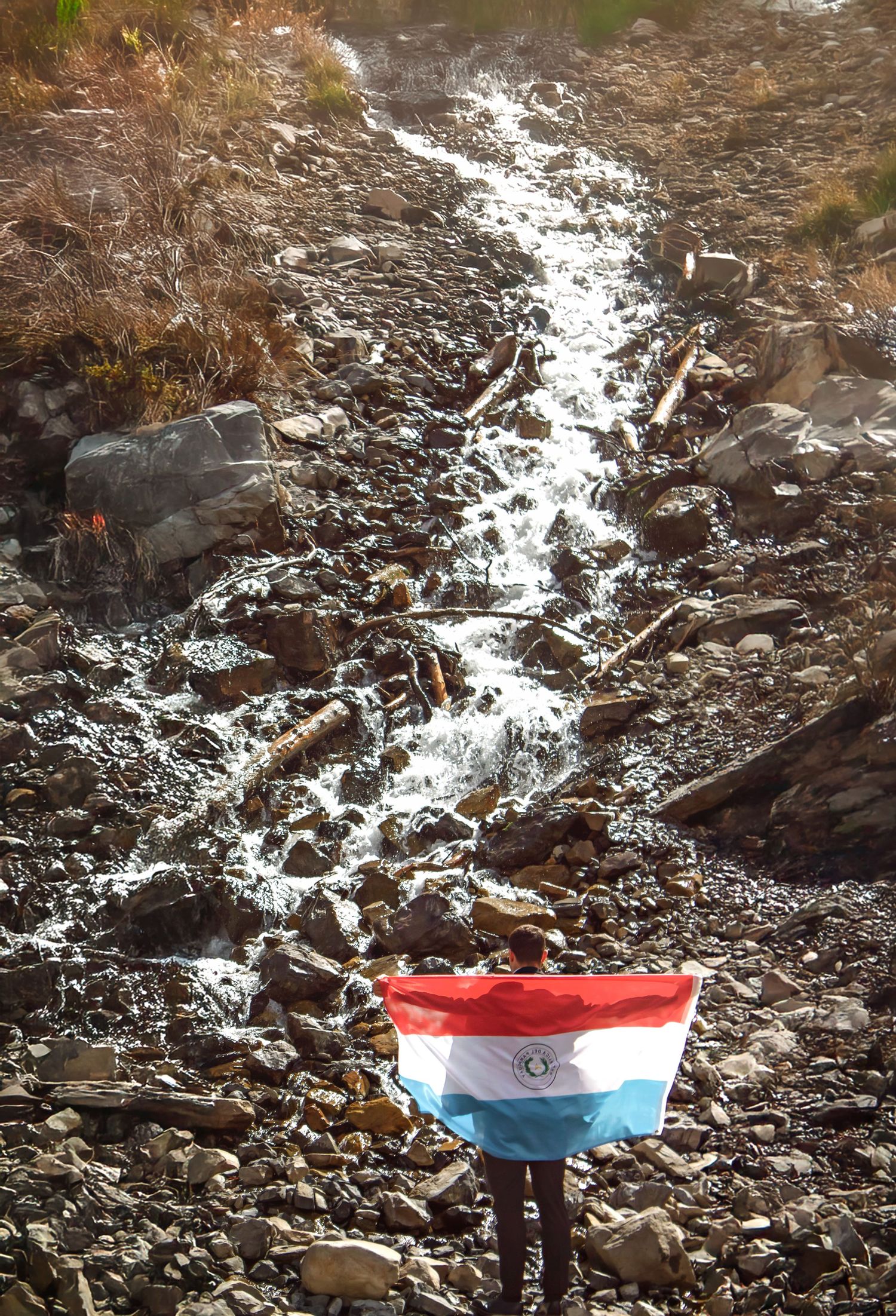 Red, white and blue flag displayed against rocky terrain with patches of snow.
