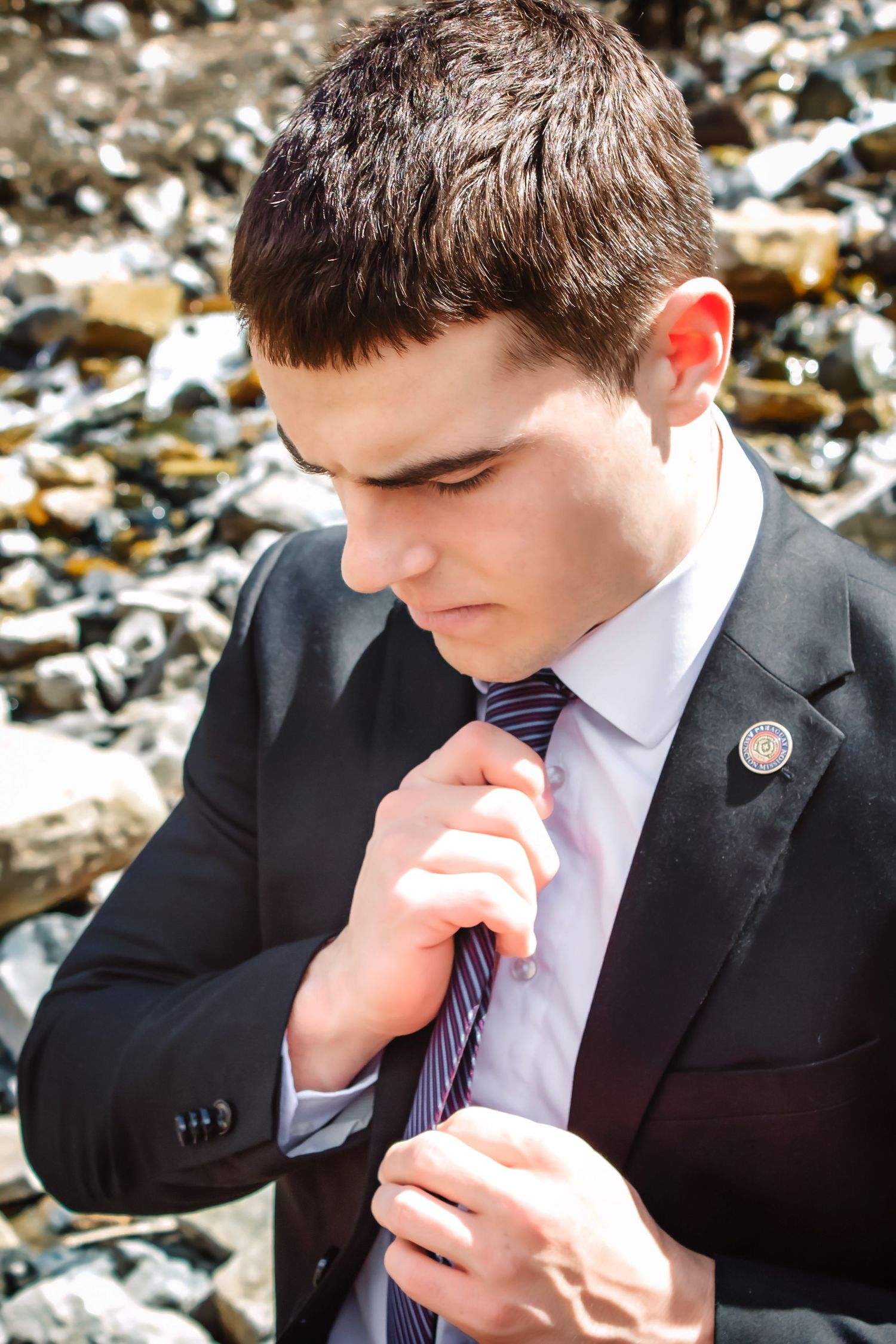 Person in formal suit and tie adjusting clothing outdoors.