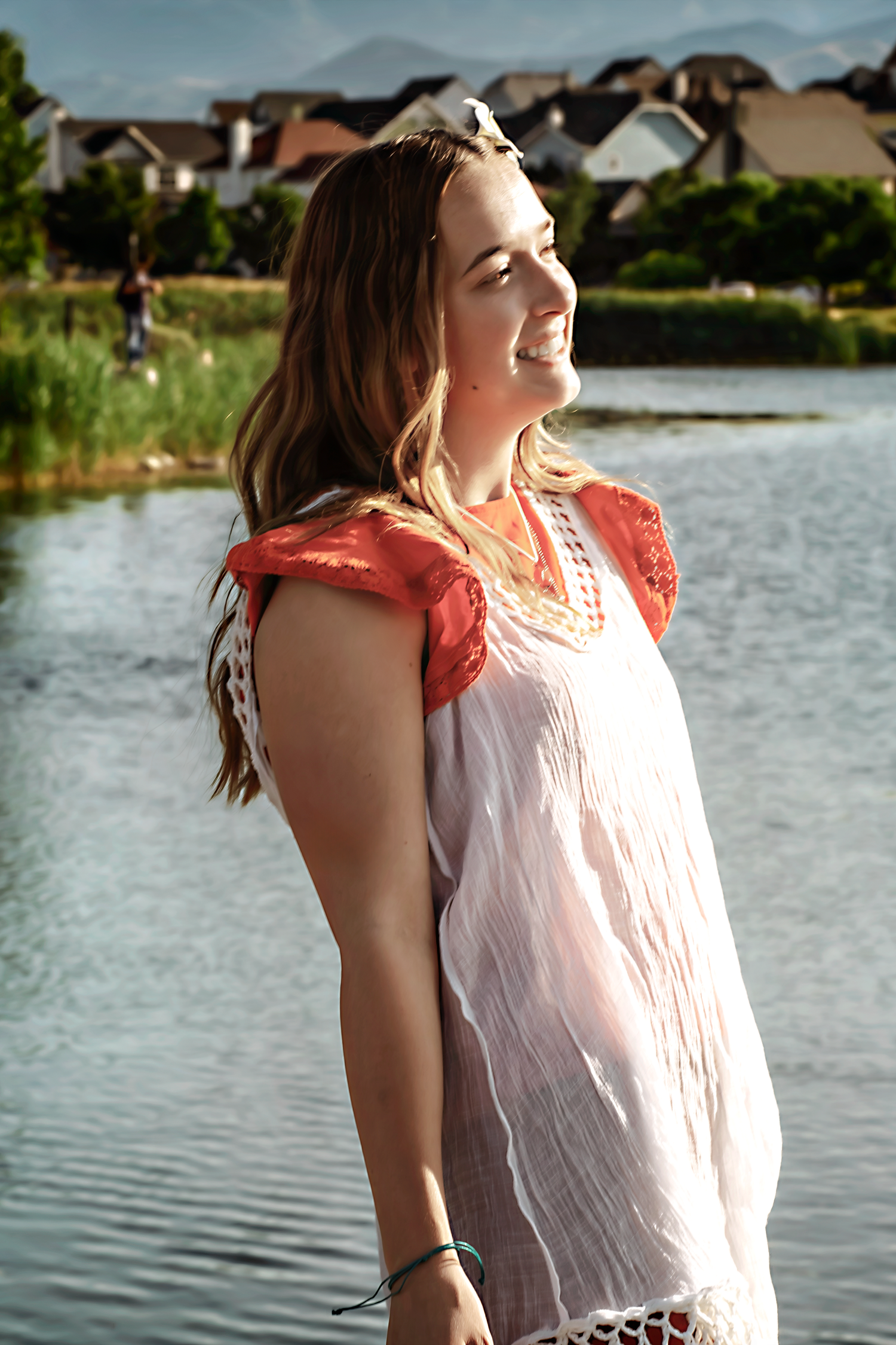 A joyful summer portrait session by the water with someone in white and coral attire.