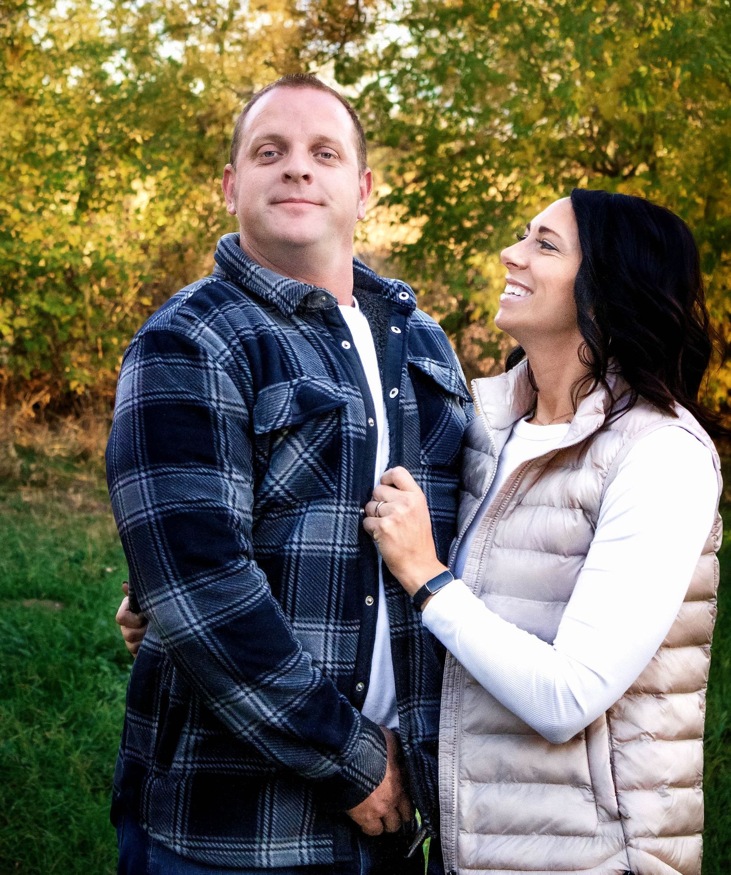 Playful outdoor photoshoot with people wearing casual winter clothing against fall trees.