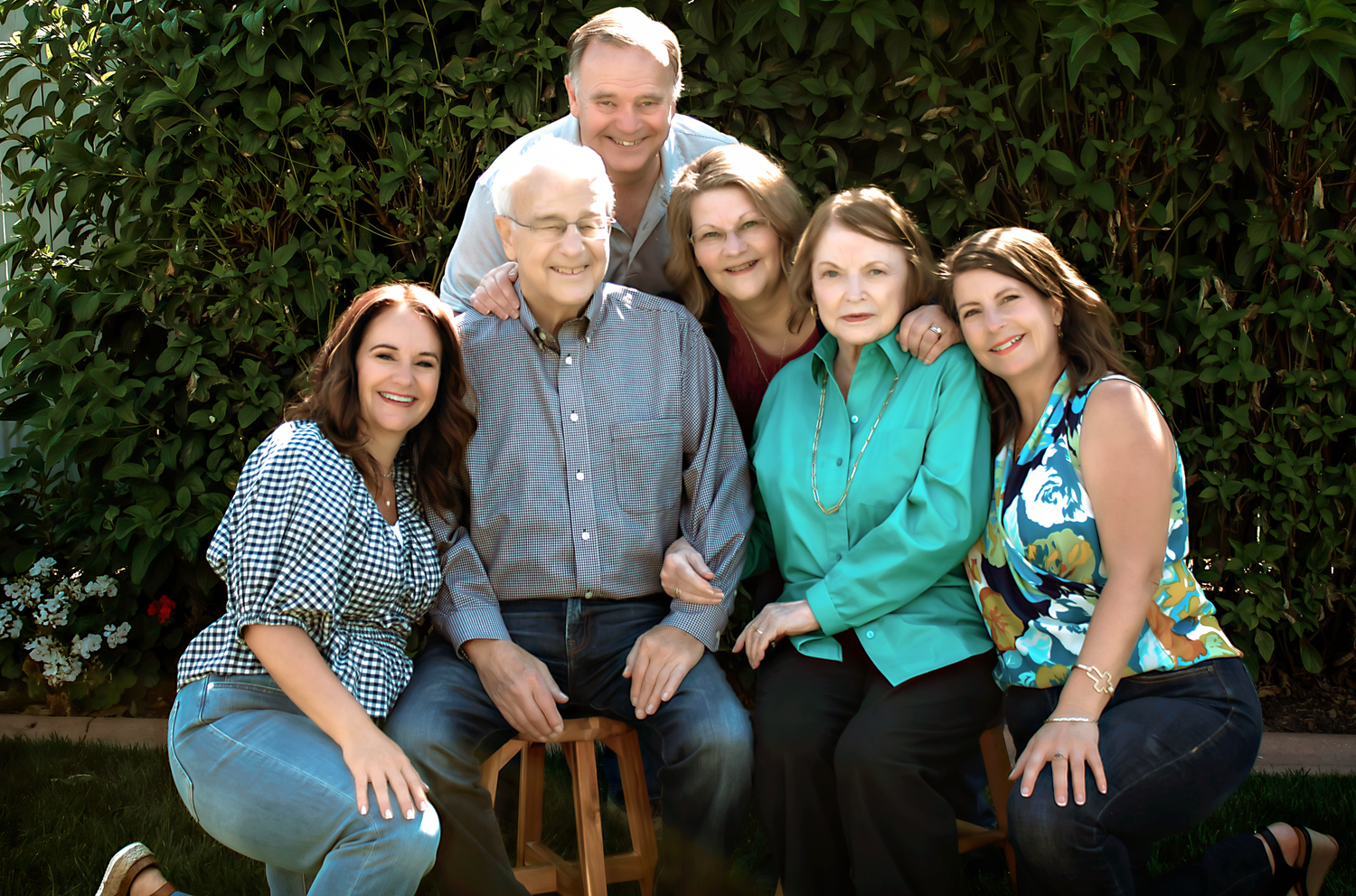 Extended family poses together on outdoor bench for multi-generational portrait.
