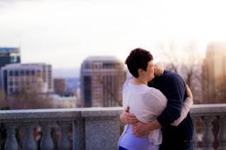Silhouetted couple embracing against urban skyline at sunset.