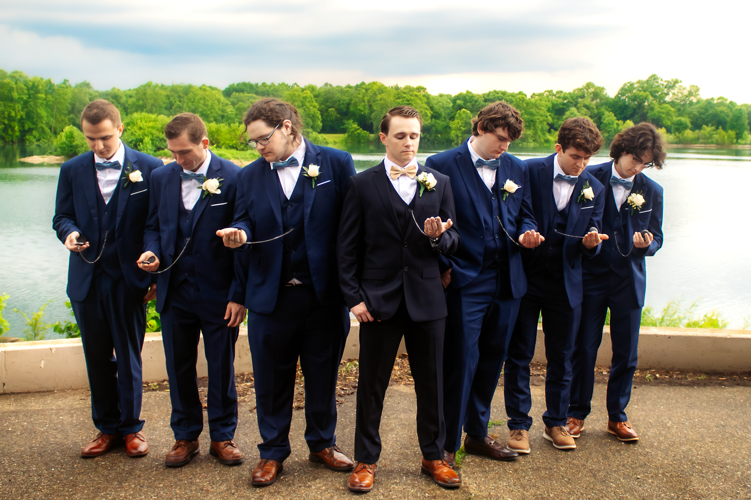 Groomsmen in navy suits show off colorful socks in coordinated group photo.