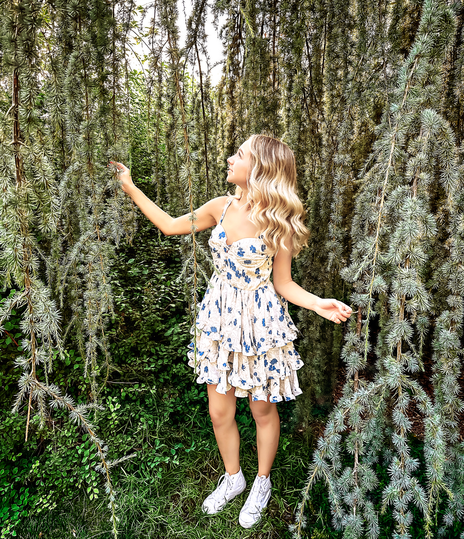 Playful outdoor photo session among silver-leafed trees in a garden setting.