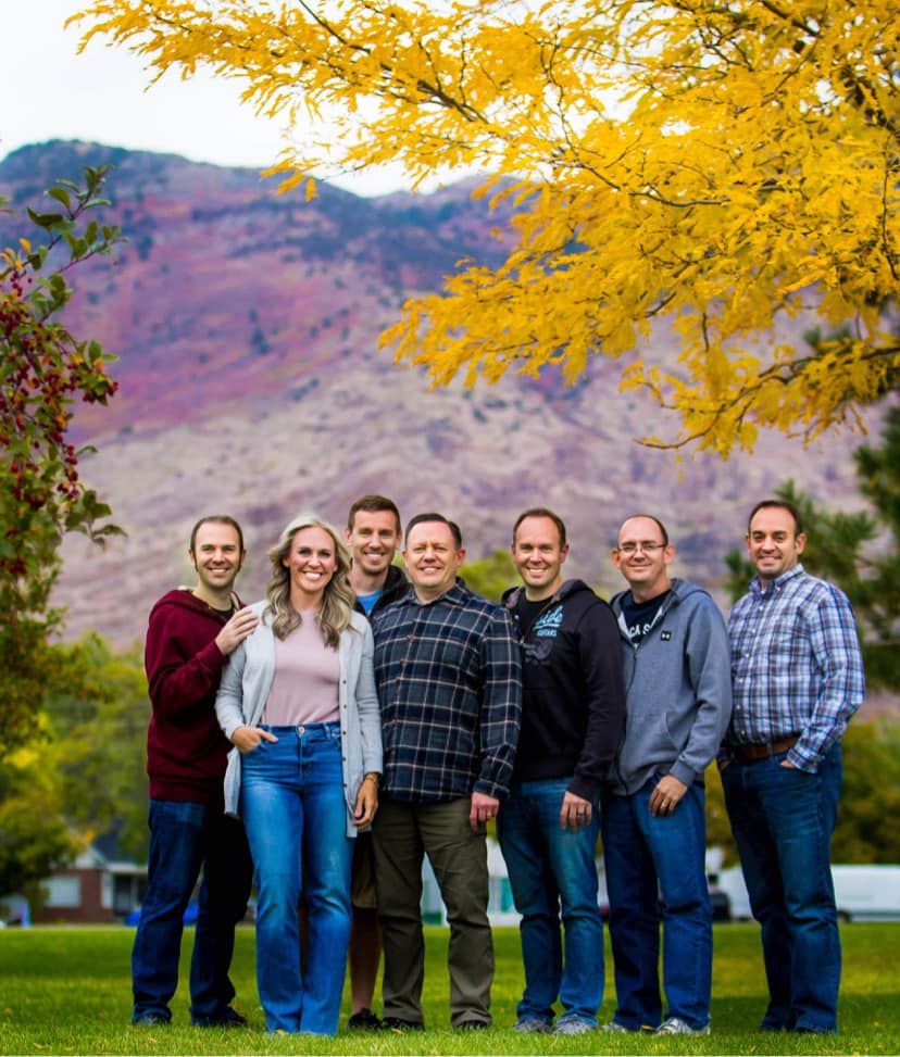 Family group photo under vibrant yellow fall foliage with mountains in background.