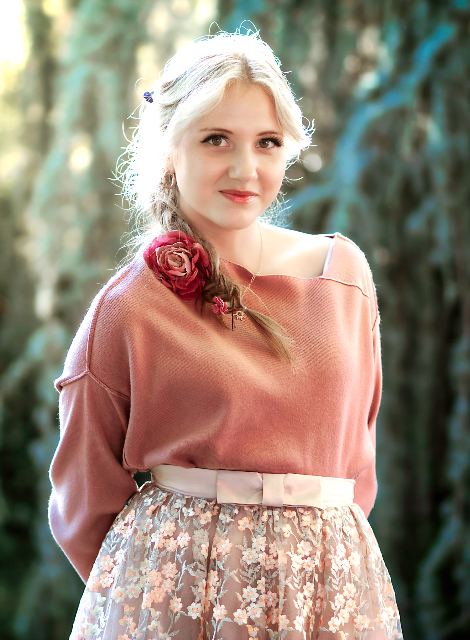 A romantic portrait in a pink dress with puff sleeves against a soft-focused natural background.