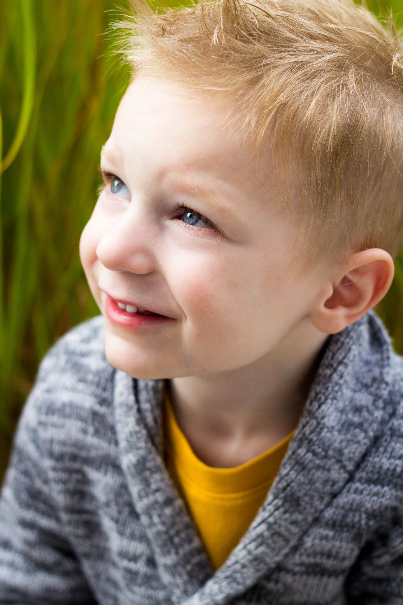 Close-up portrait series of young child in gray sweater showing various expressions.