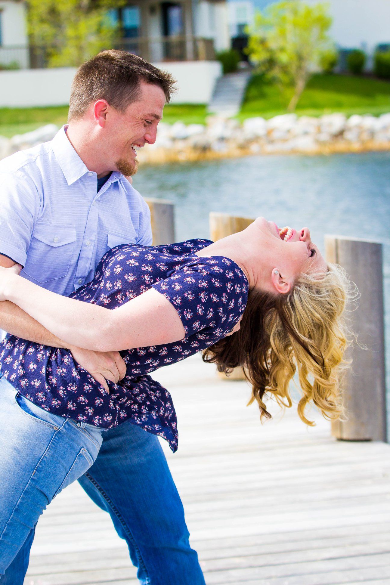 Romantic dip pose sequence on a waterfront dock during engagement photos.
