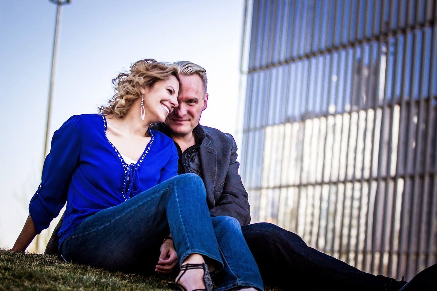 Couple shares intimate moment against industrial backdrop with blue and metal tones.