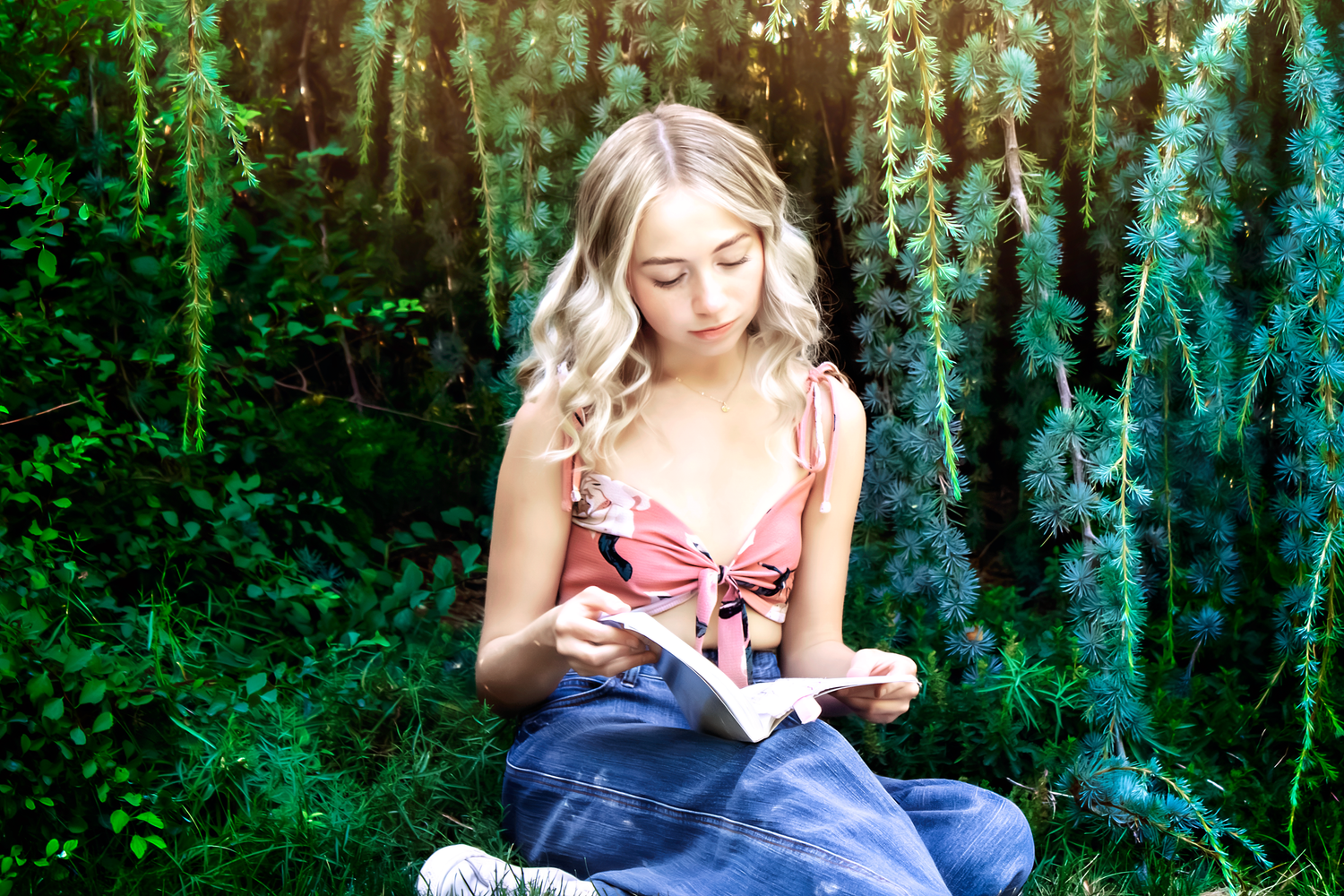 Figure in denim sits against forest backdrop reading outdoors.