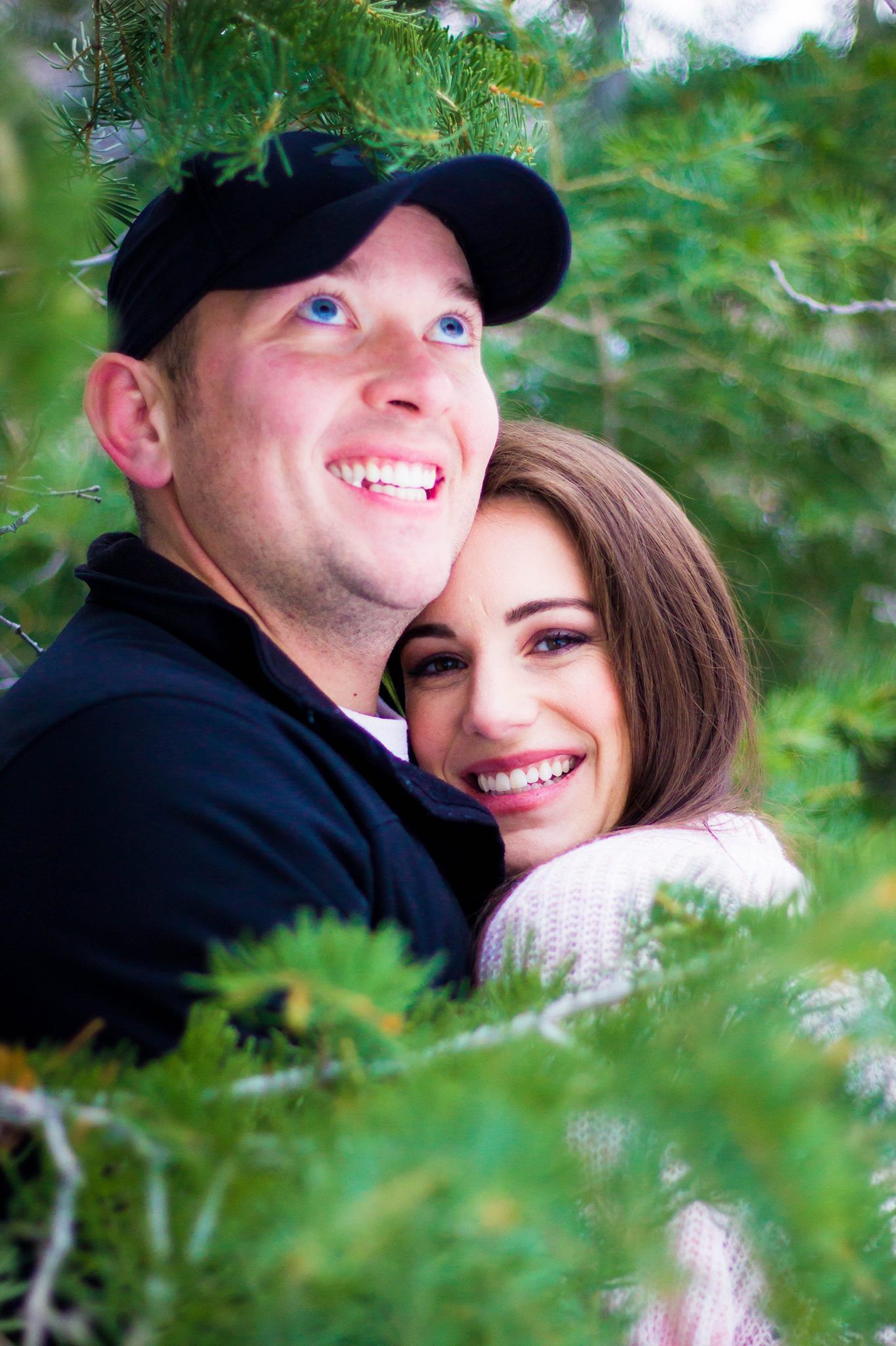 Romantic outdoor portraits framed by green foliage showing genuine smiles and connection.