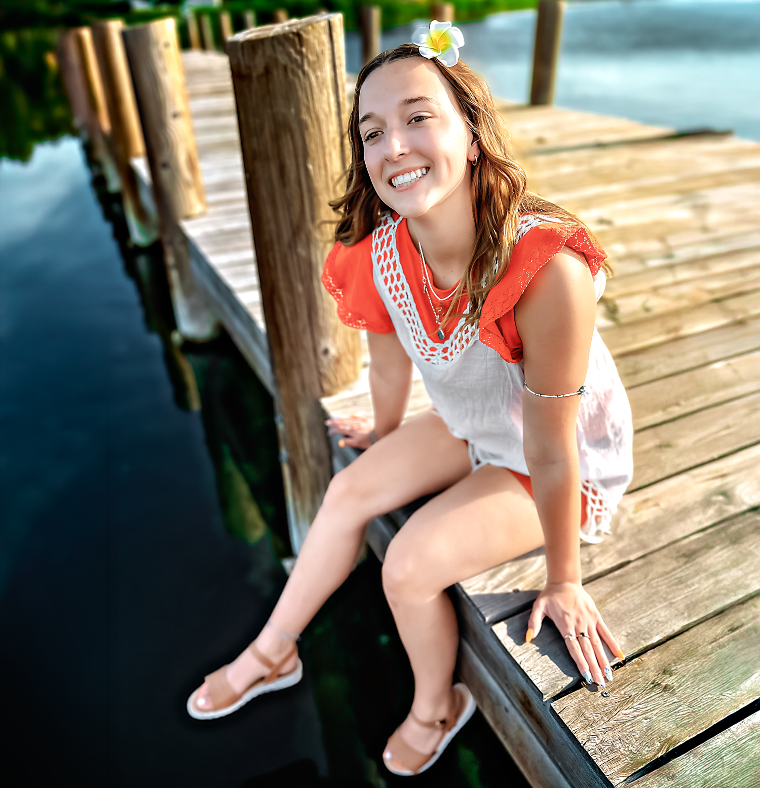 Person relaxing on wooden pier with white flower in hair.