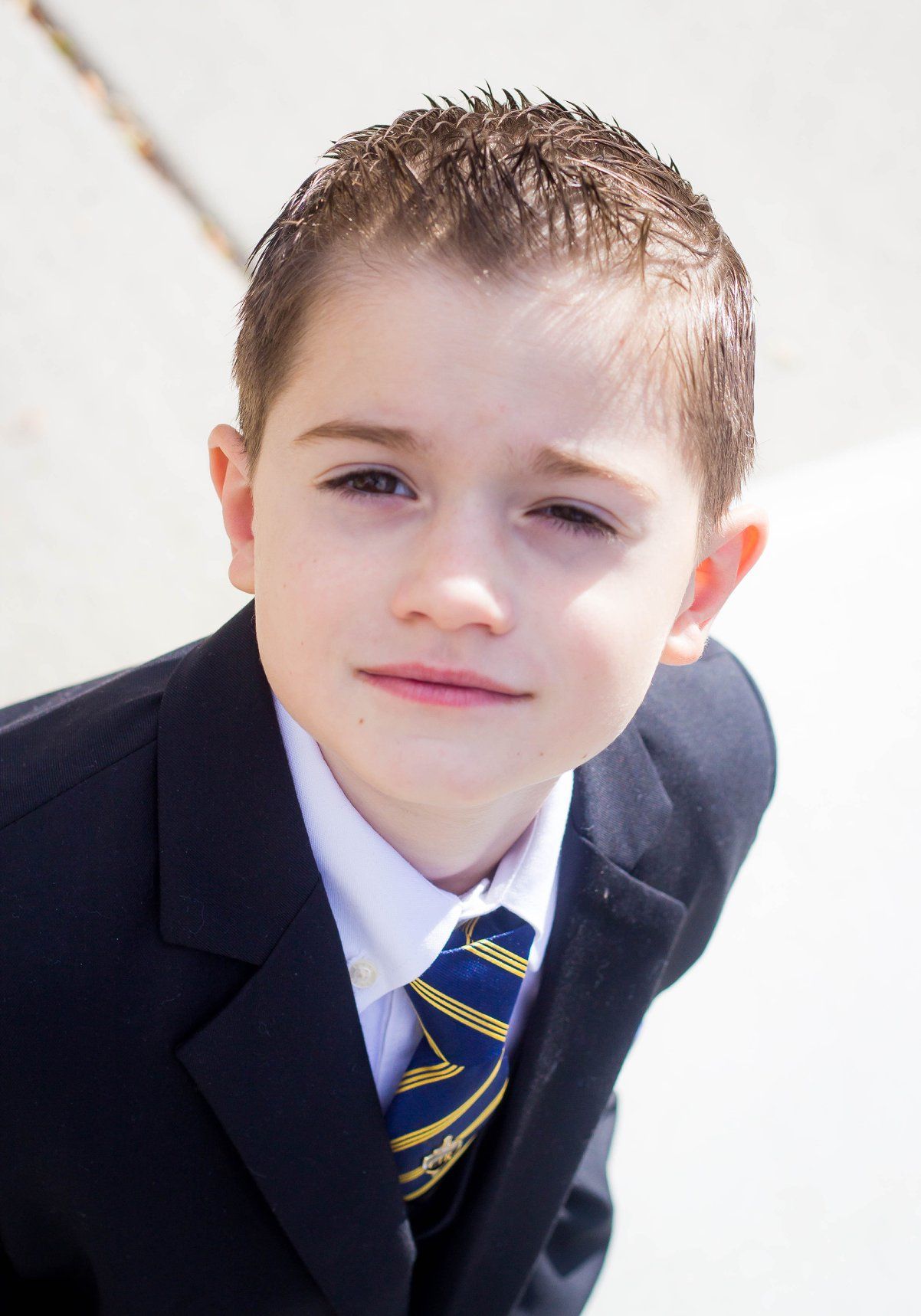 Child in formal suit and tie poses for close-up portrait shots.