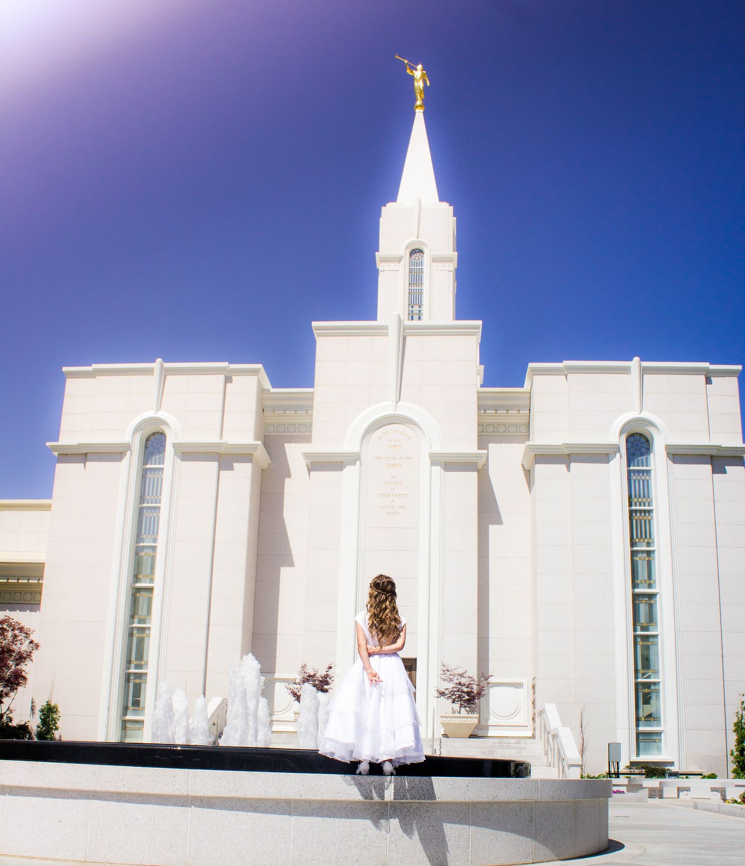 White Mormon temple building photographed against bright blue sky.
