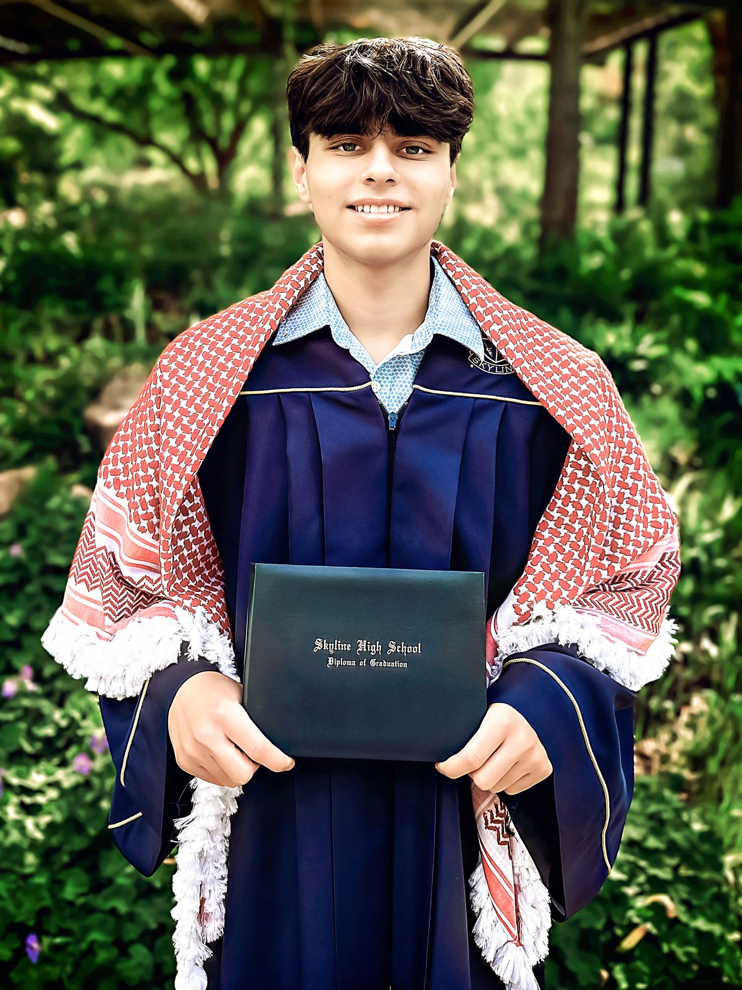 Graduate in navy gown holding diploma while posing in outdoor setting.