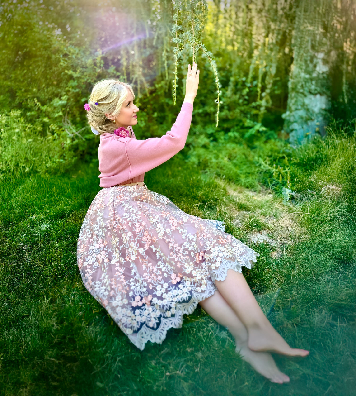 Person in pink dress sitting dreamily in a lush garden setting with soft lighting.