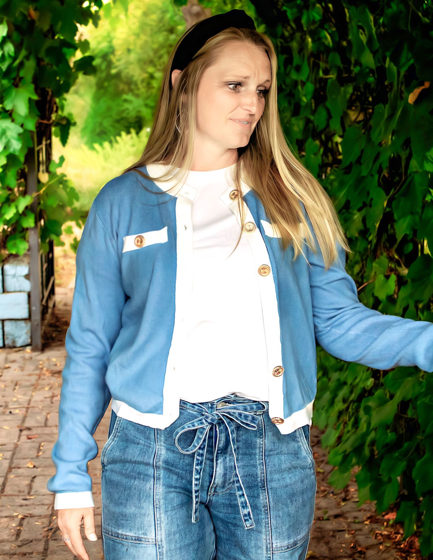 Casual outfit featuring light blue jacket with white trim and high-waisted jeans in garden setting.