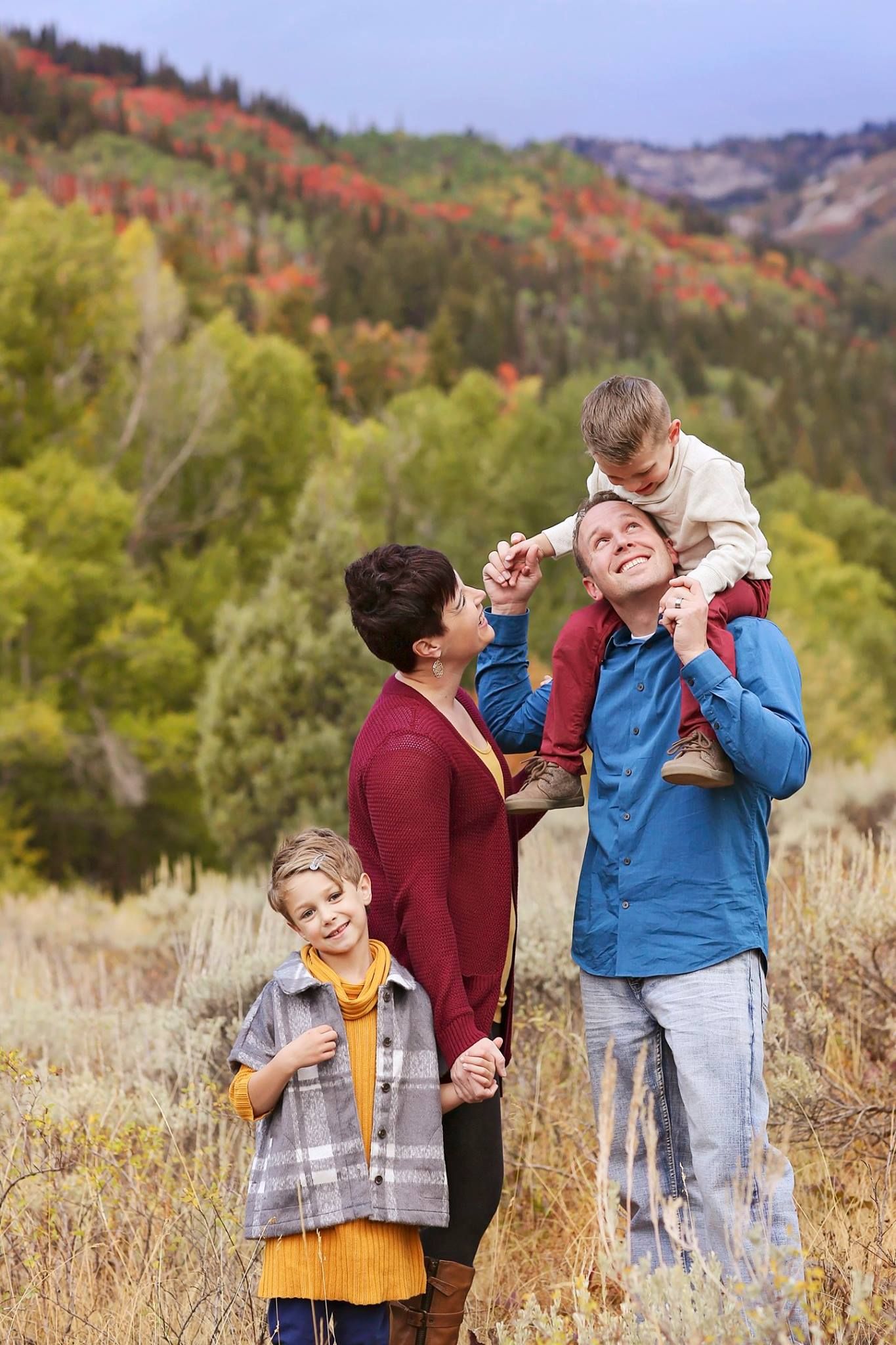Family shares joyful interactions in scenic mountain meadow during fall.