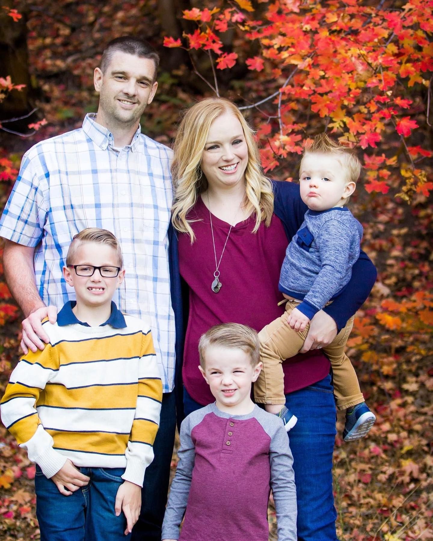 Family portrait series with coordinated outfits in burgundy and blue against colorful fall leaves.