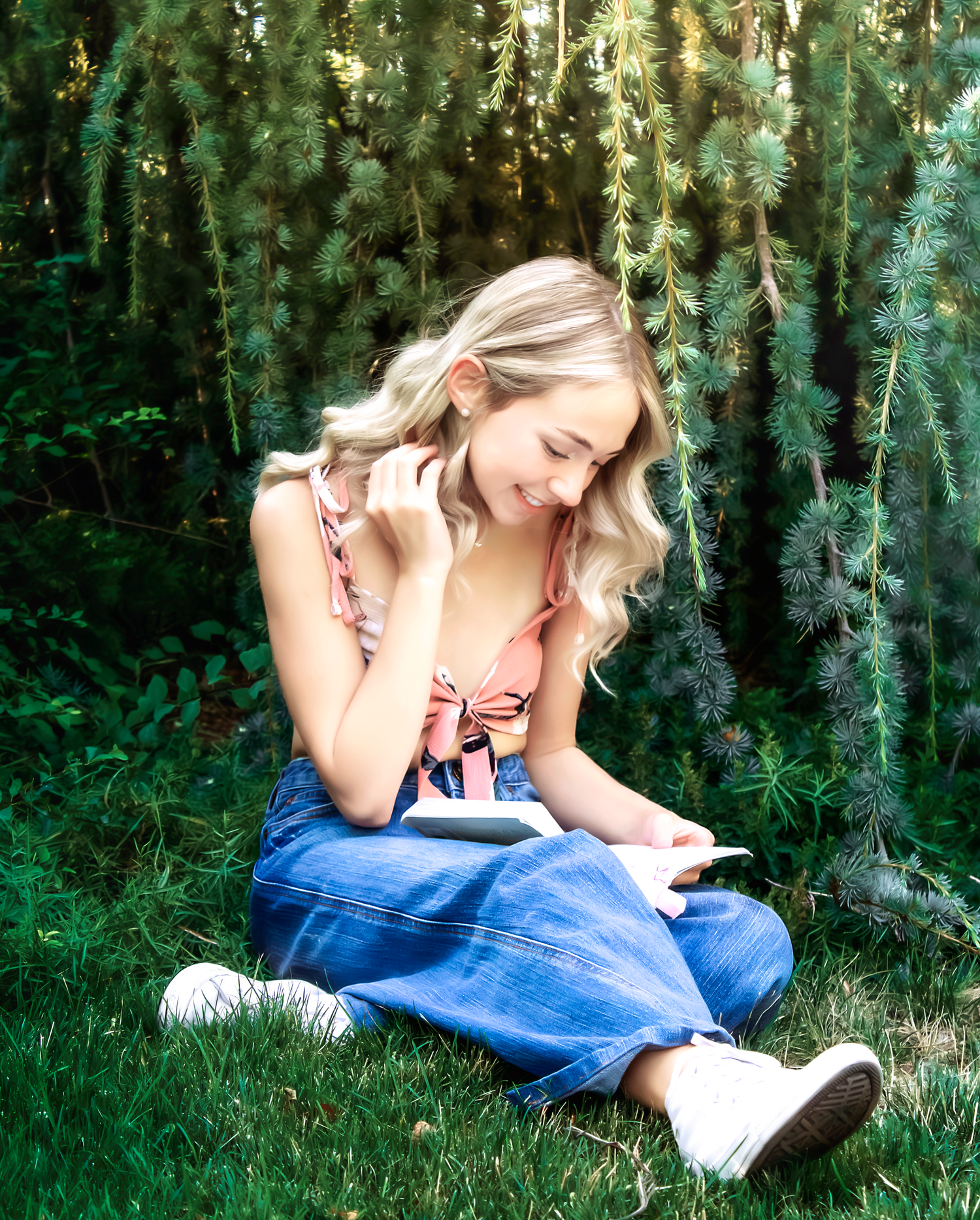 Someone reads while lounging on grass in a peaceful forest setting.