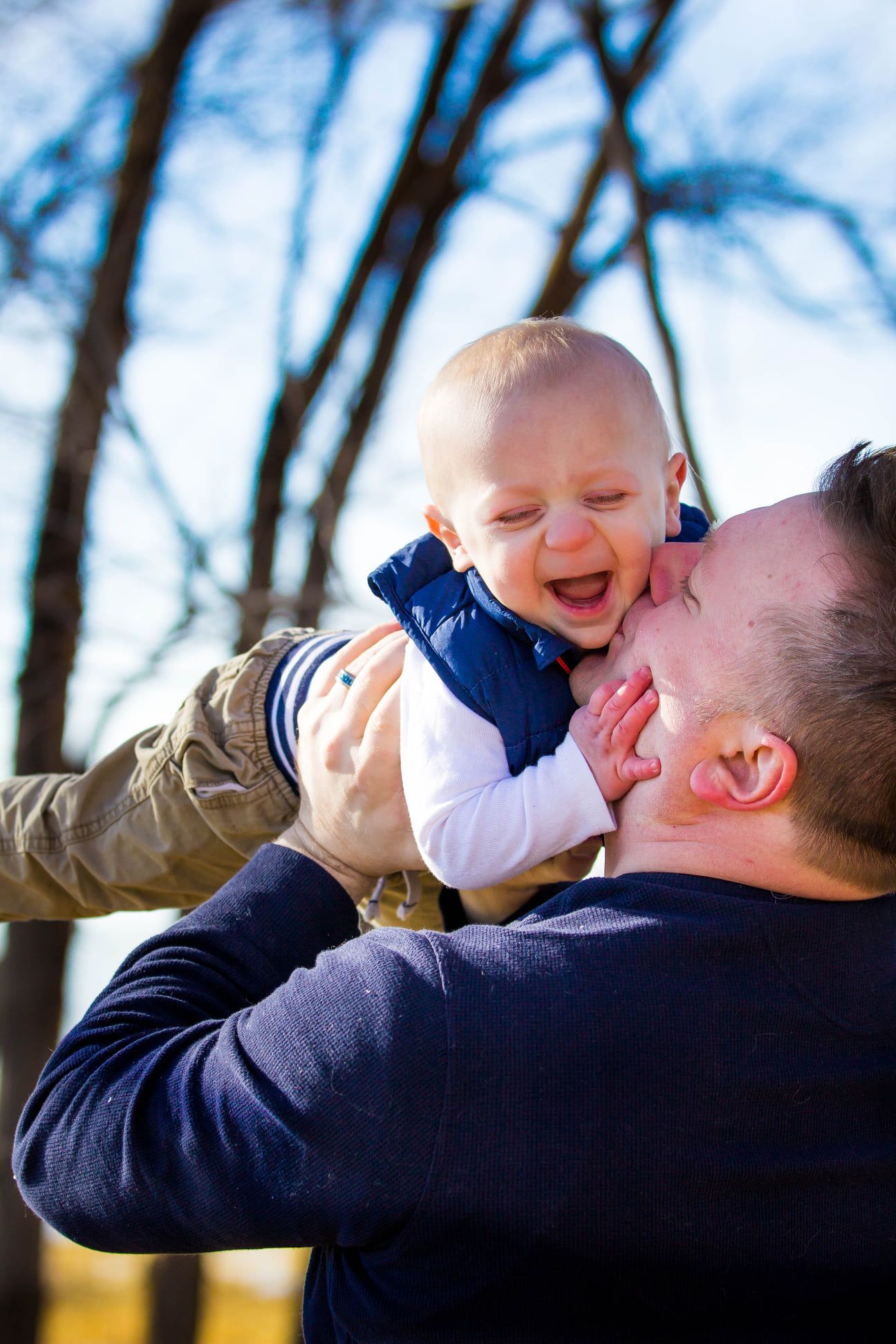 Joyful moments captured between parent and child against blue sky background.