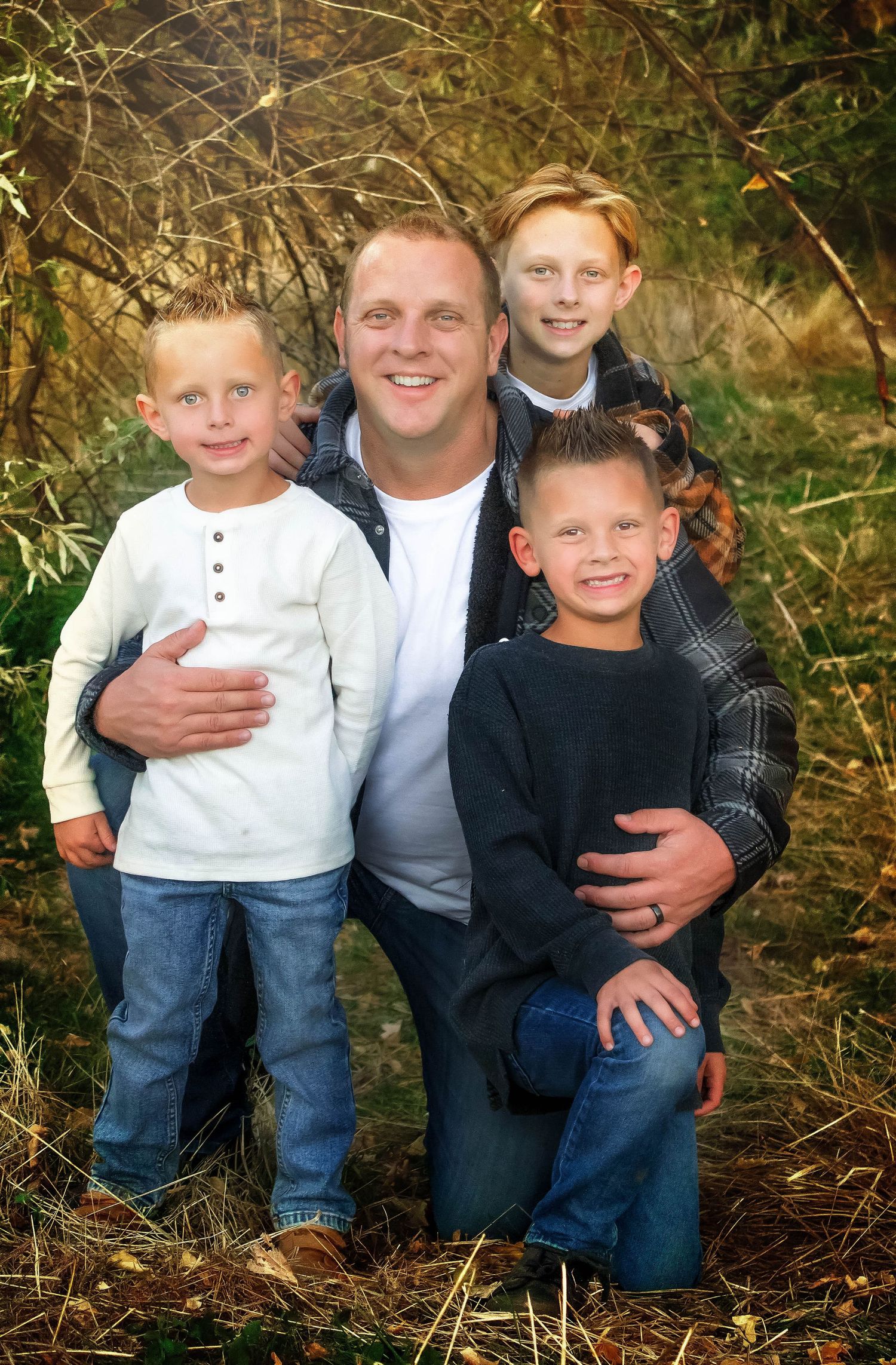 Family group wearing casual clothing poses together outdoors in natural setting.