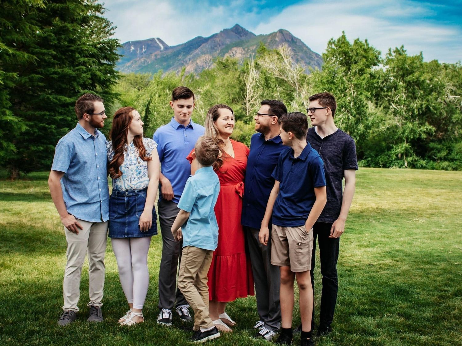 Outdoor group gathering with mountains and blue sky in background.