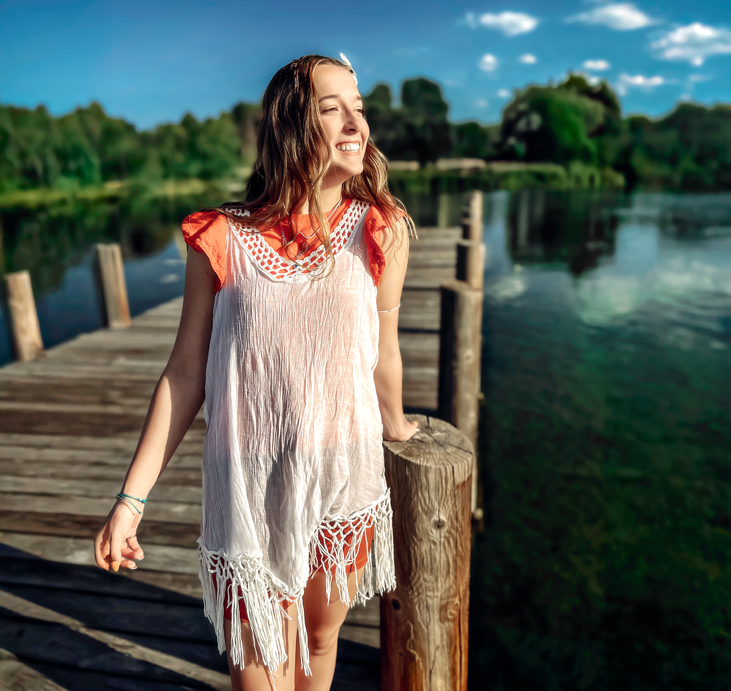 White and coral summer outfit against scenic lake backdrop.