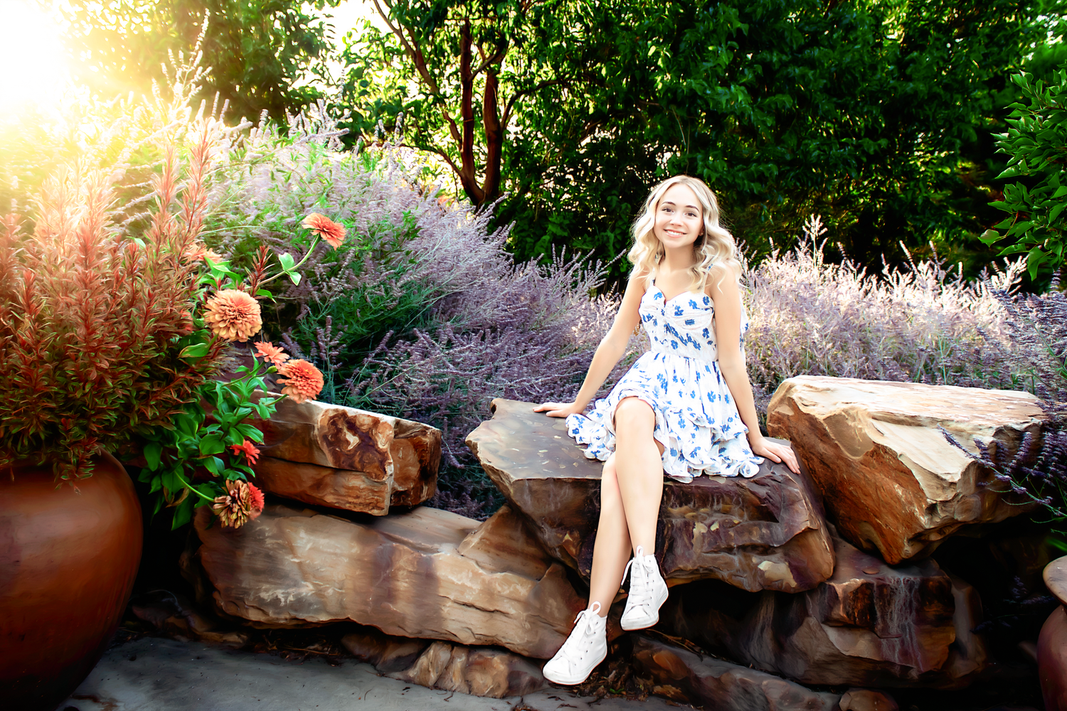 Summer garden scene with stone wall and flowering plants during sunset.