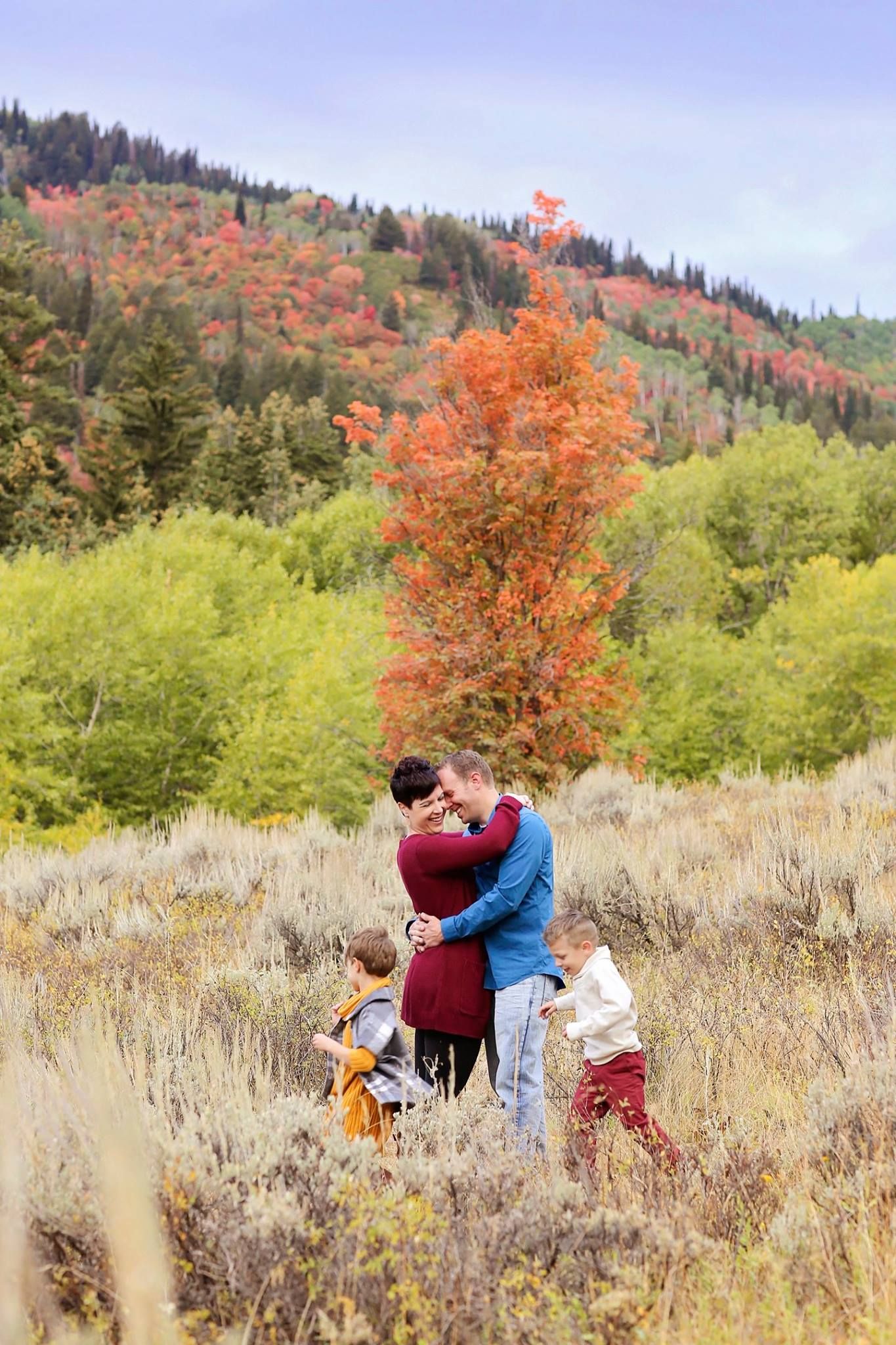 Family playing together in mountain meadow with fall foliage.