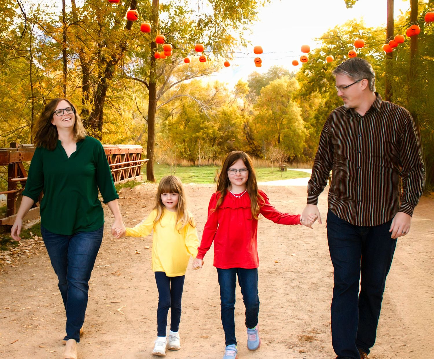 Family members stroll together on a nature trail surrounded by fall foliage.