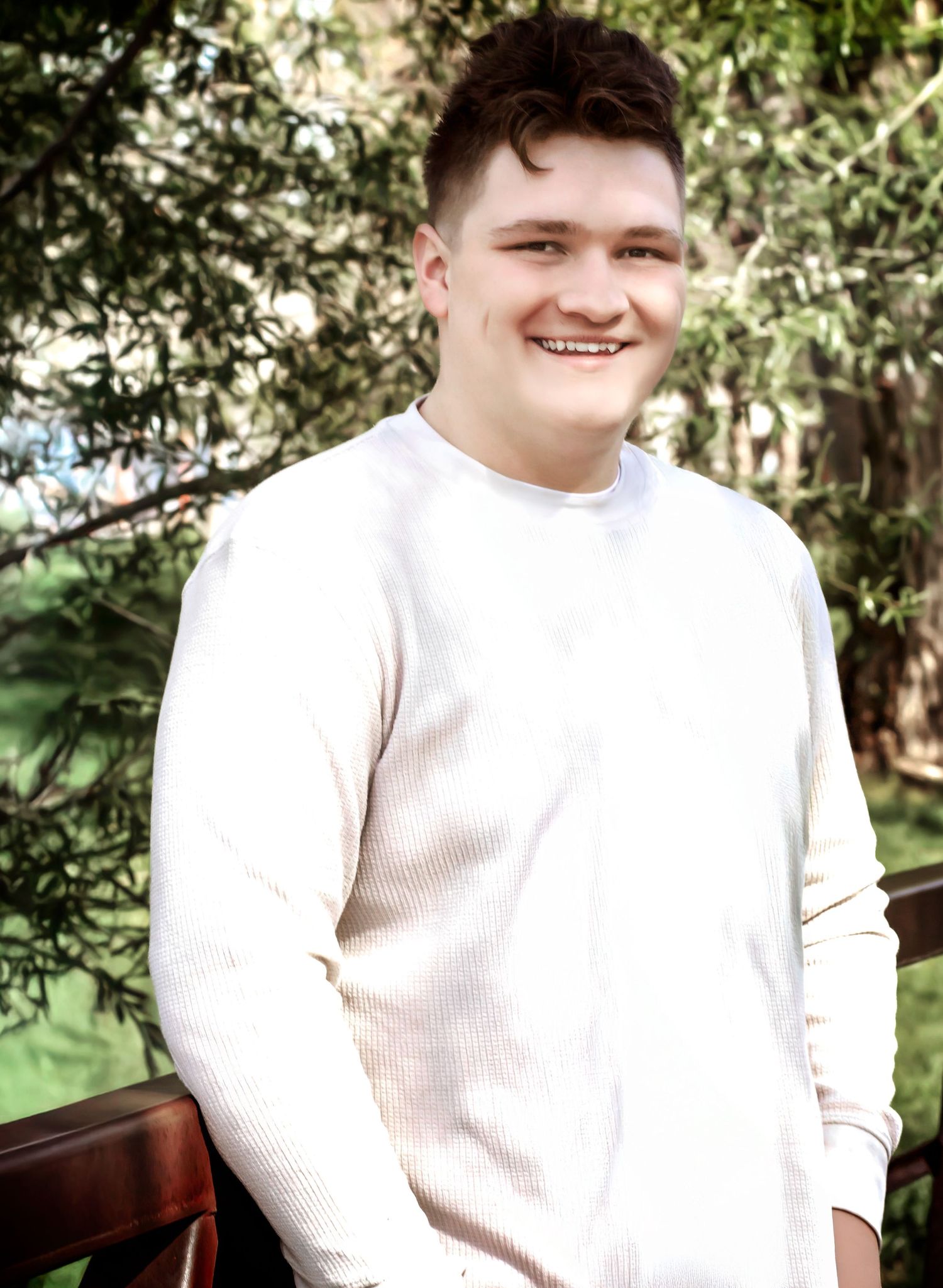 Portrait in natural lighting wearing white ribbed sweater against garden background.