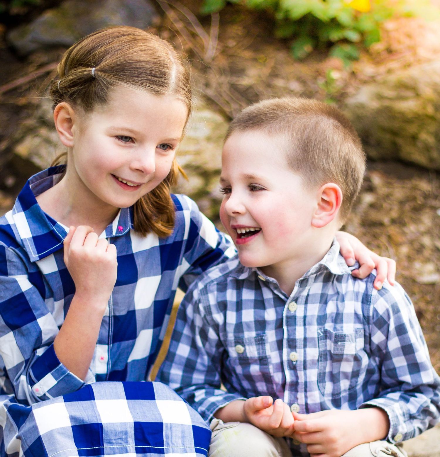 Two people in blue and white checkered clothing sharing laughs outdoors.