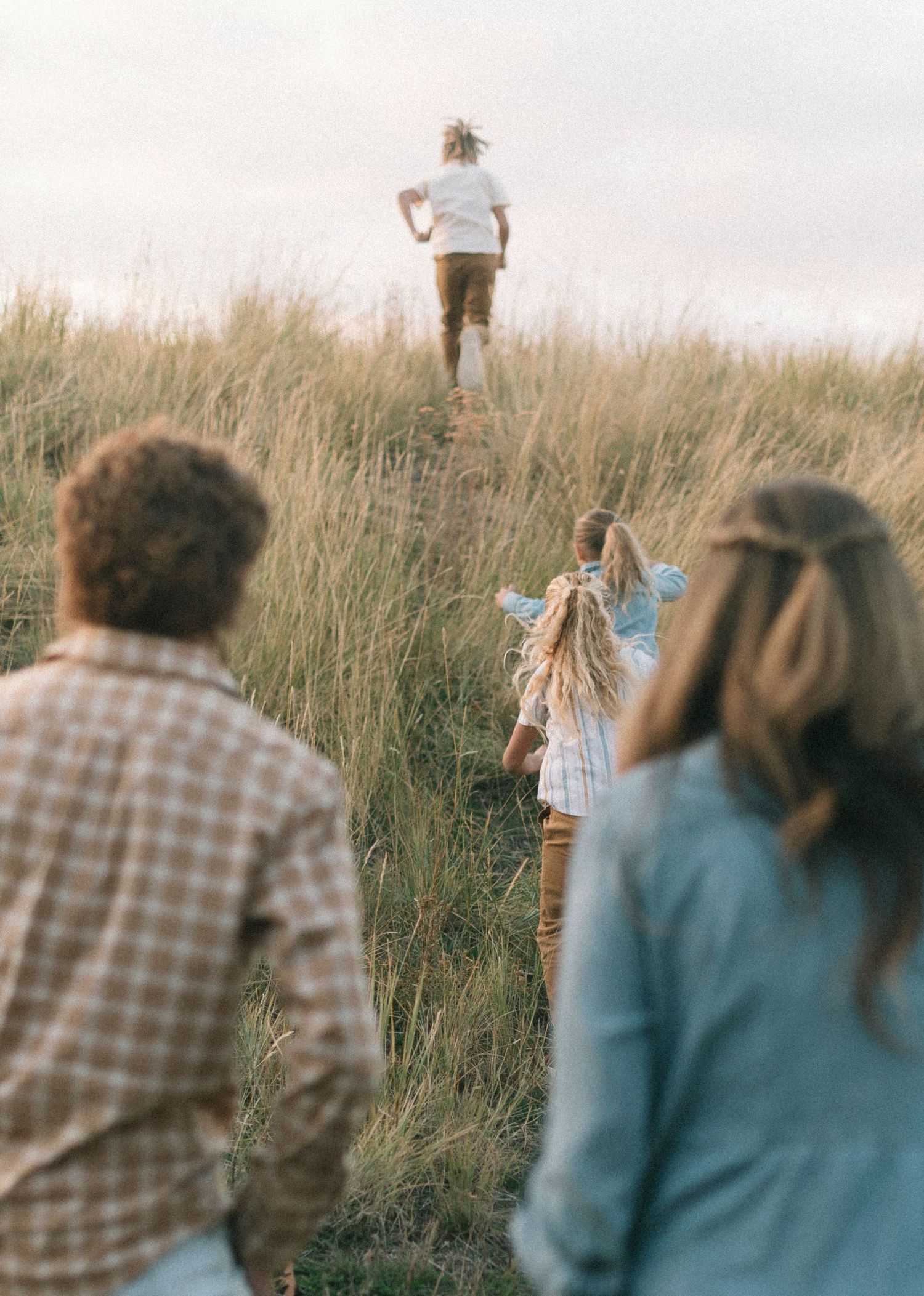 People watching someone run up a grassy hill during golden hour.