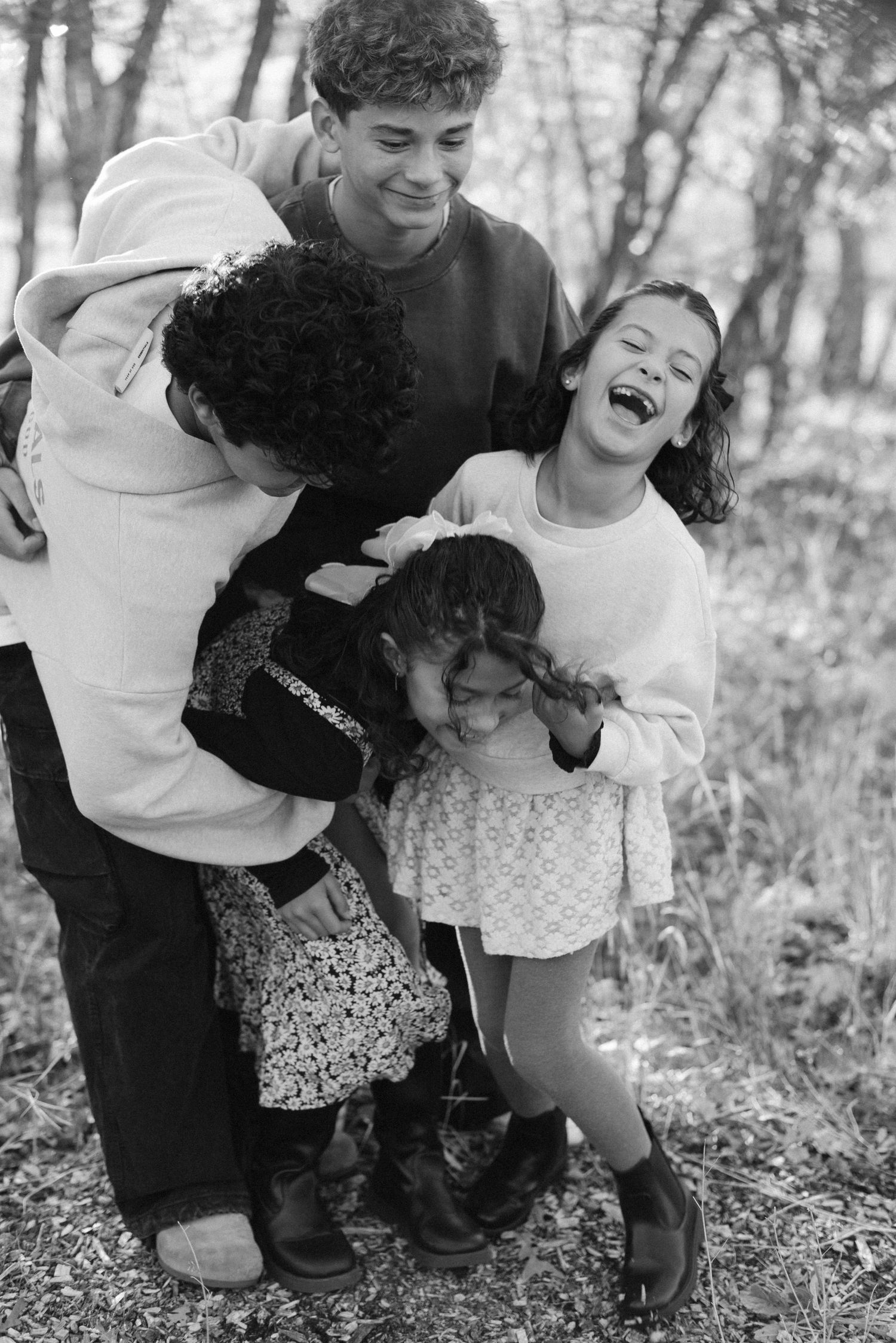 A joyful black and white family portrait with everyone laughing together outdoors.