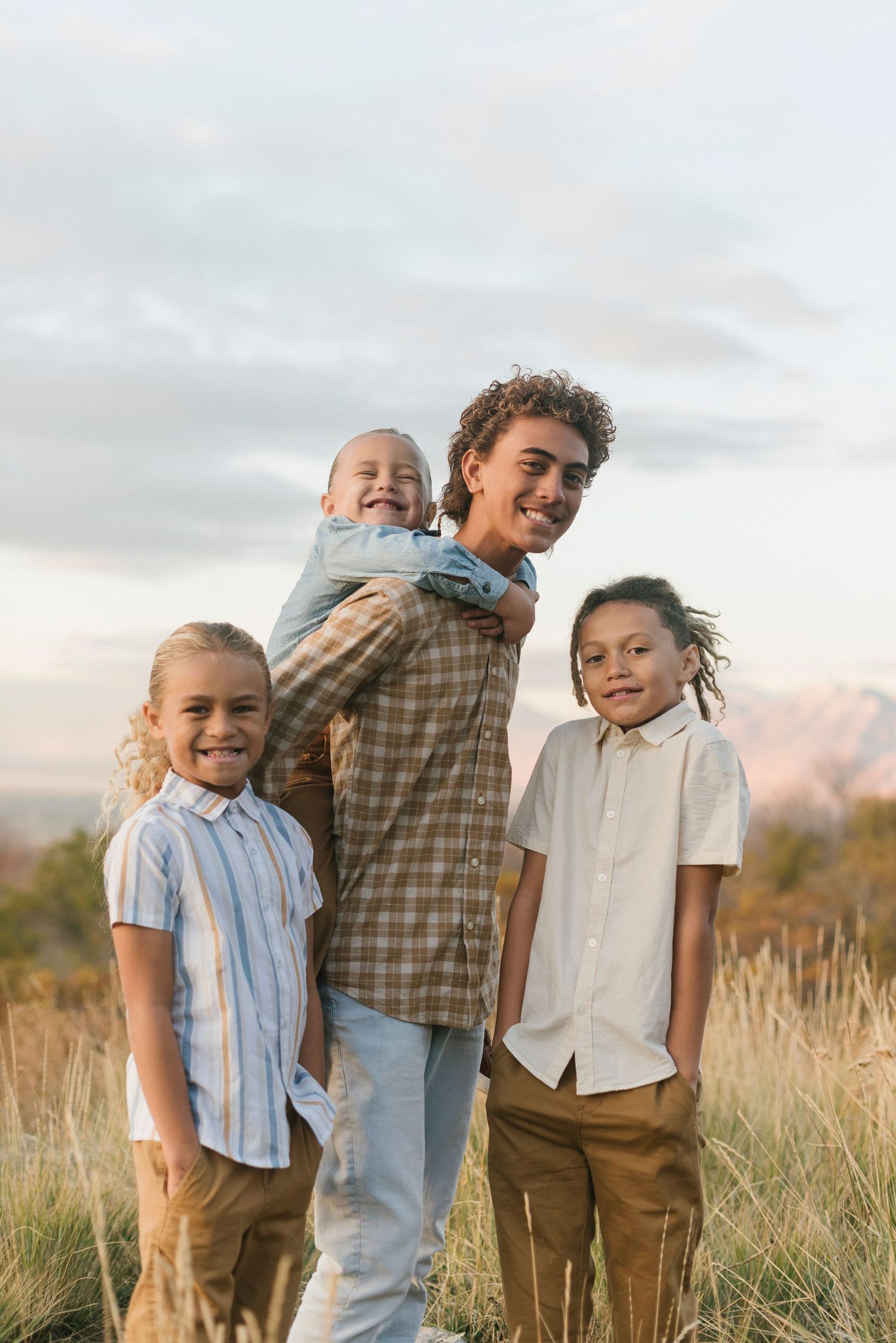 A group poses together outdoors in a field of tall grass during golden hour.