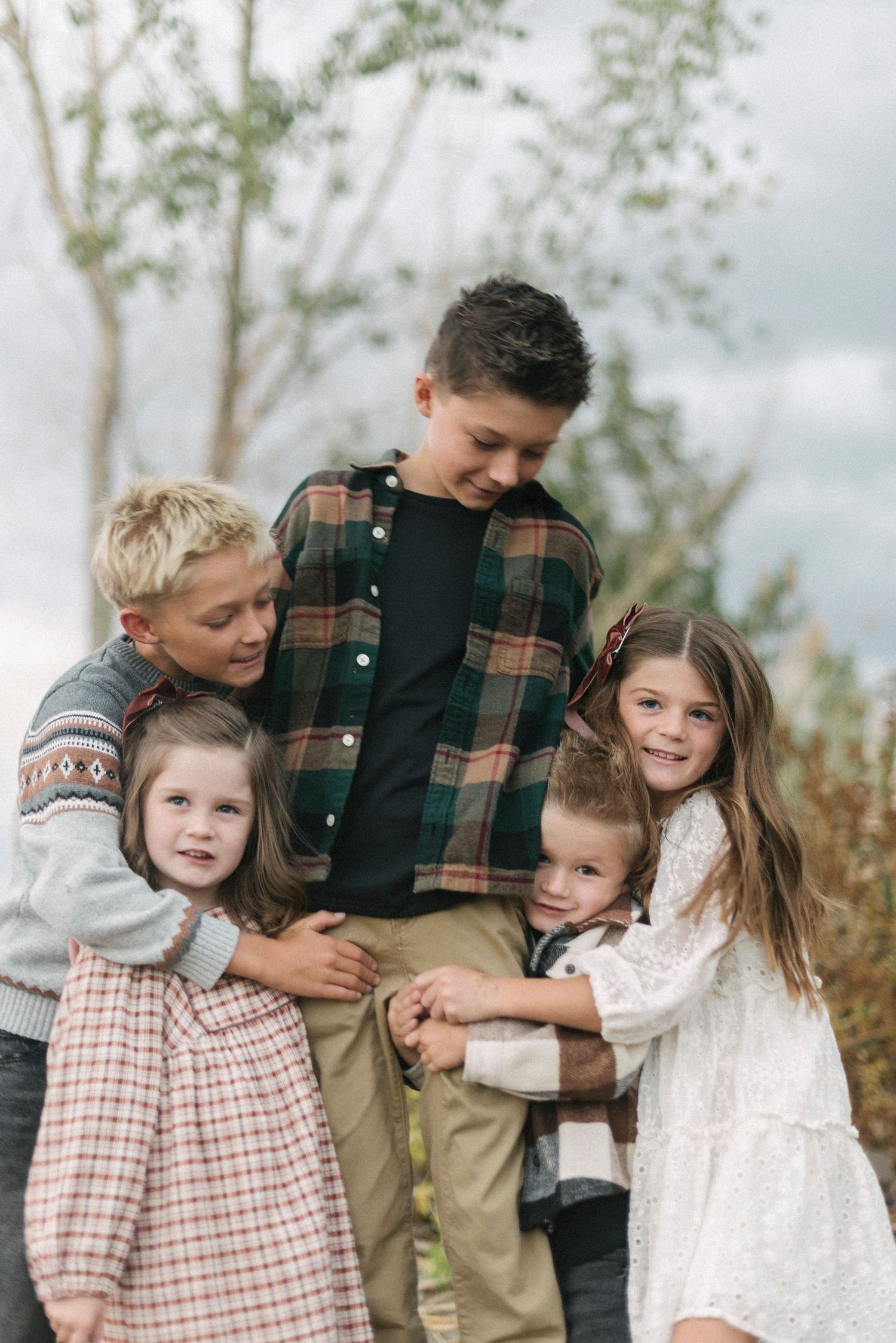 Family group portrait outdoors with coordinated outfits in plaid and white.