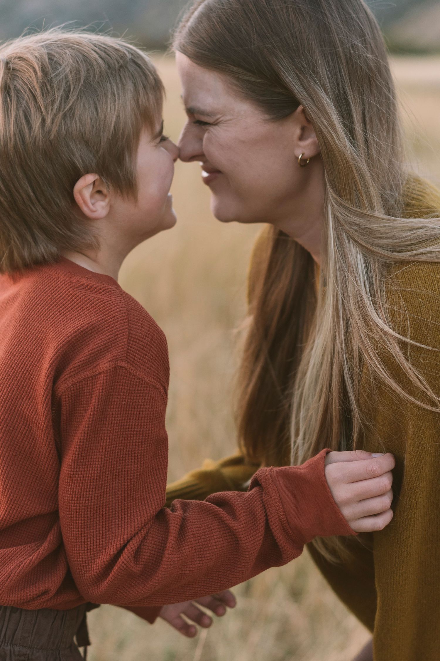 Tender interaction between two people in matching rust-colored sweaters against a natural backdrop.