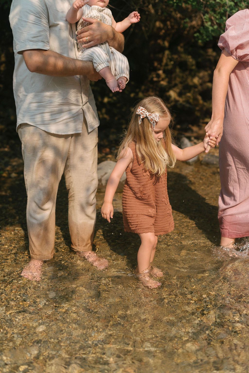 Family enjoying time together standing in shallow water on a sunny day.