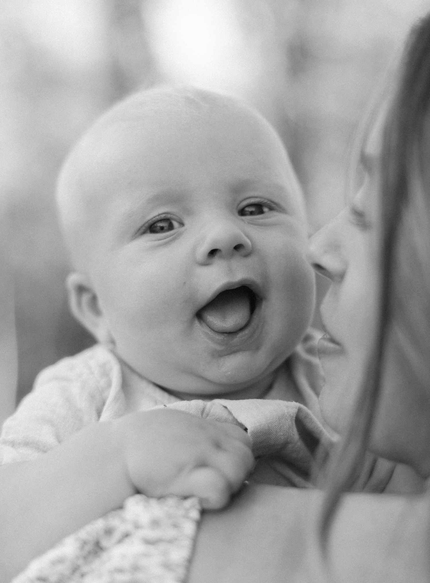 Black and white close-up portraits of a smiling baby showing various expressions.