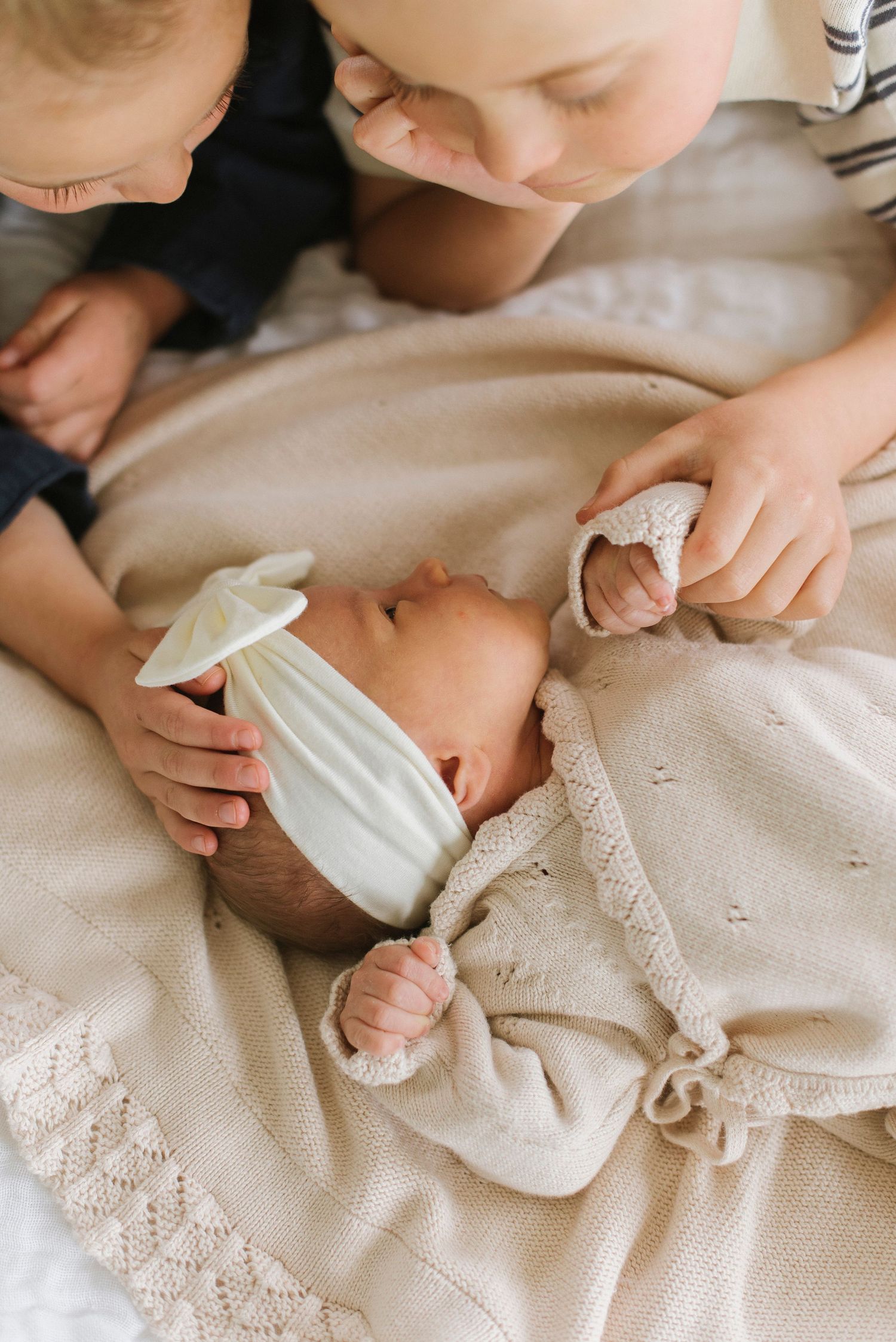 Close-up details of tiny baby hands and feet with delicate white lace clothing.