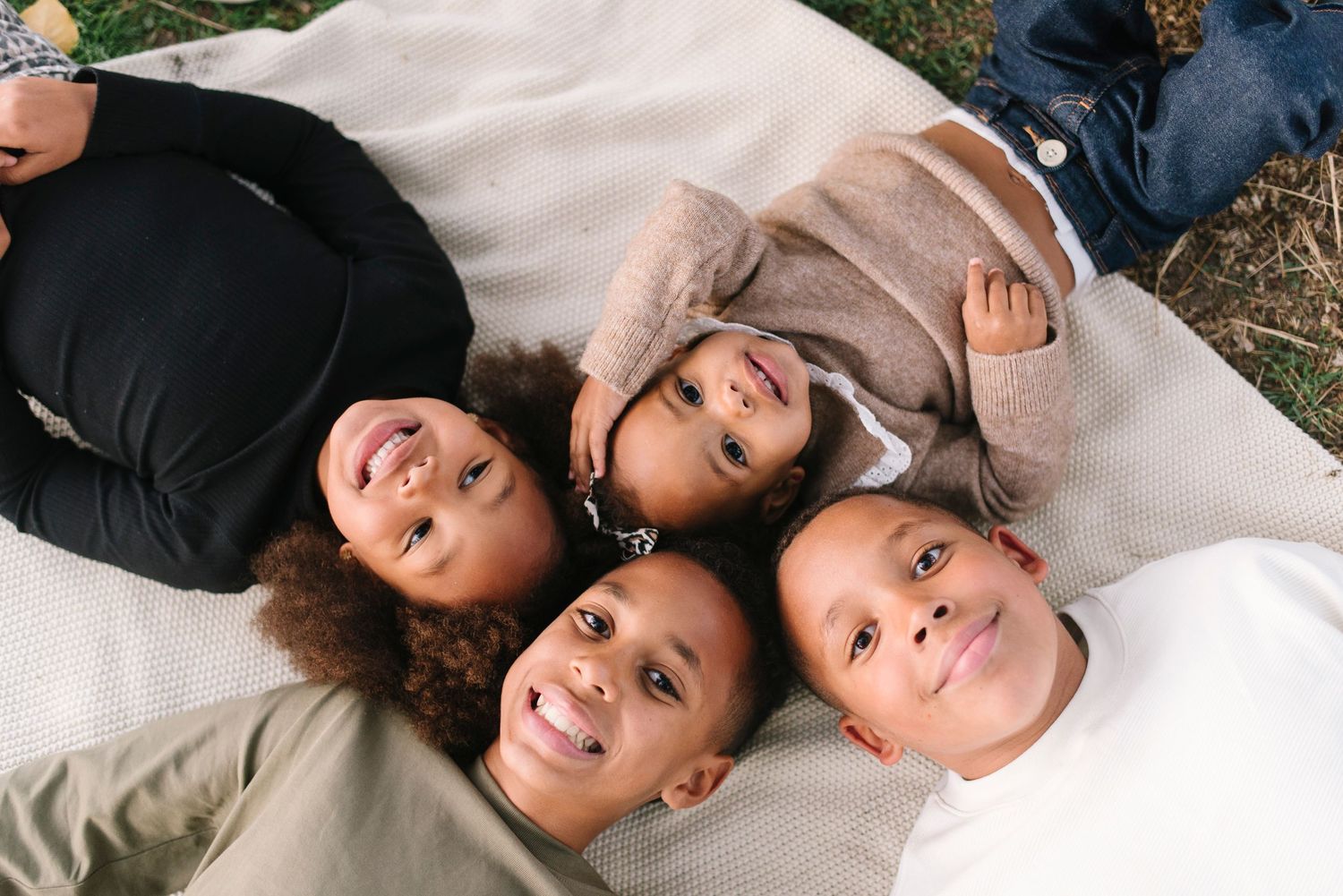 A group lying down together on a white blanket outdoors, captured from above.