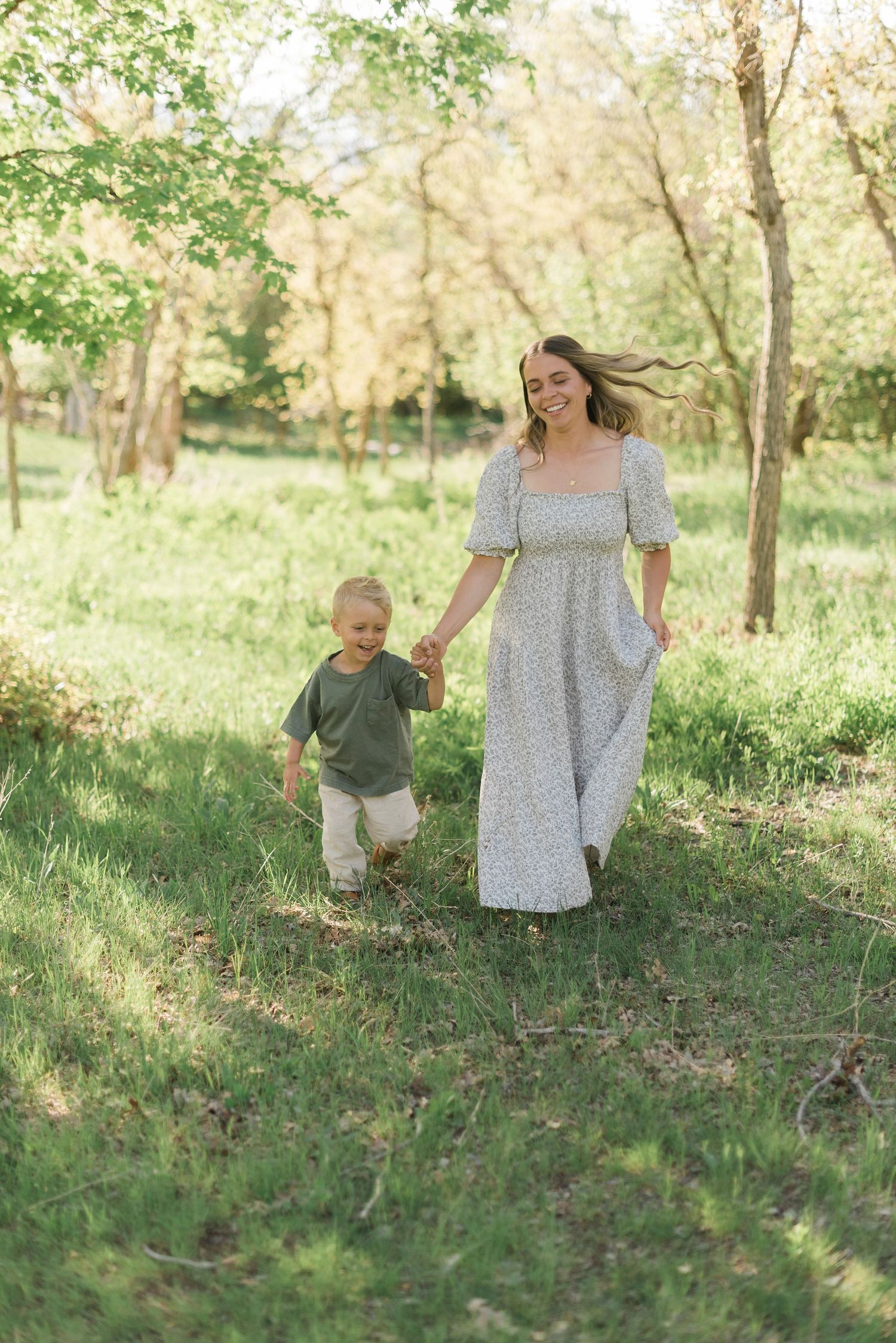 A playful chase sequence in a sun-dappled meadow with spring greenery.