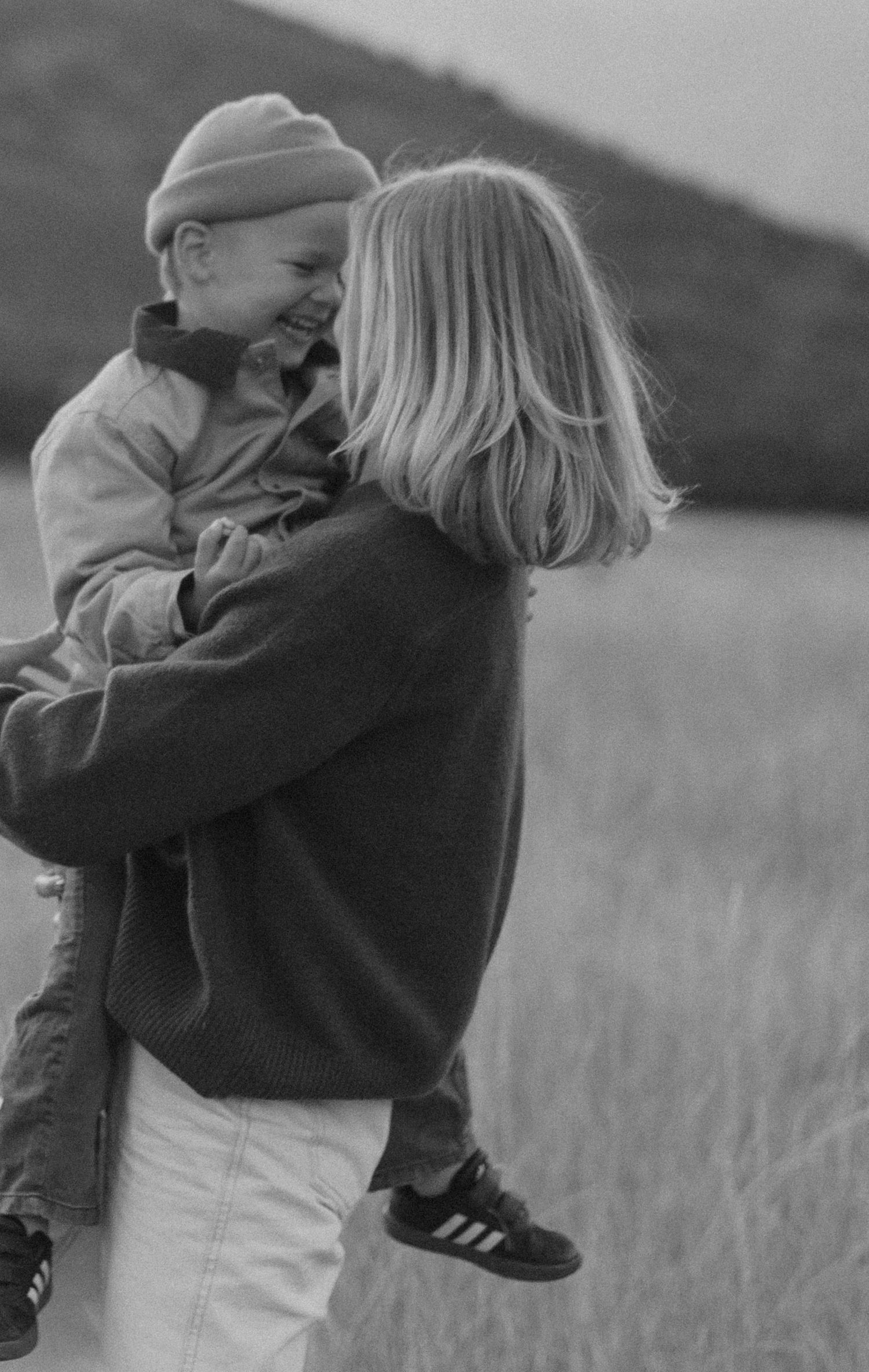 Candid black and white photos of a tender moment between two people in a field.