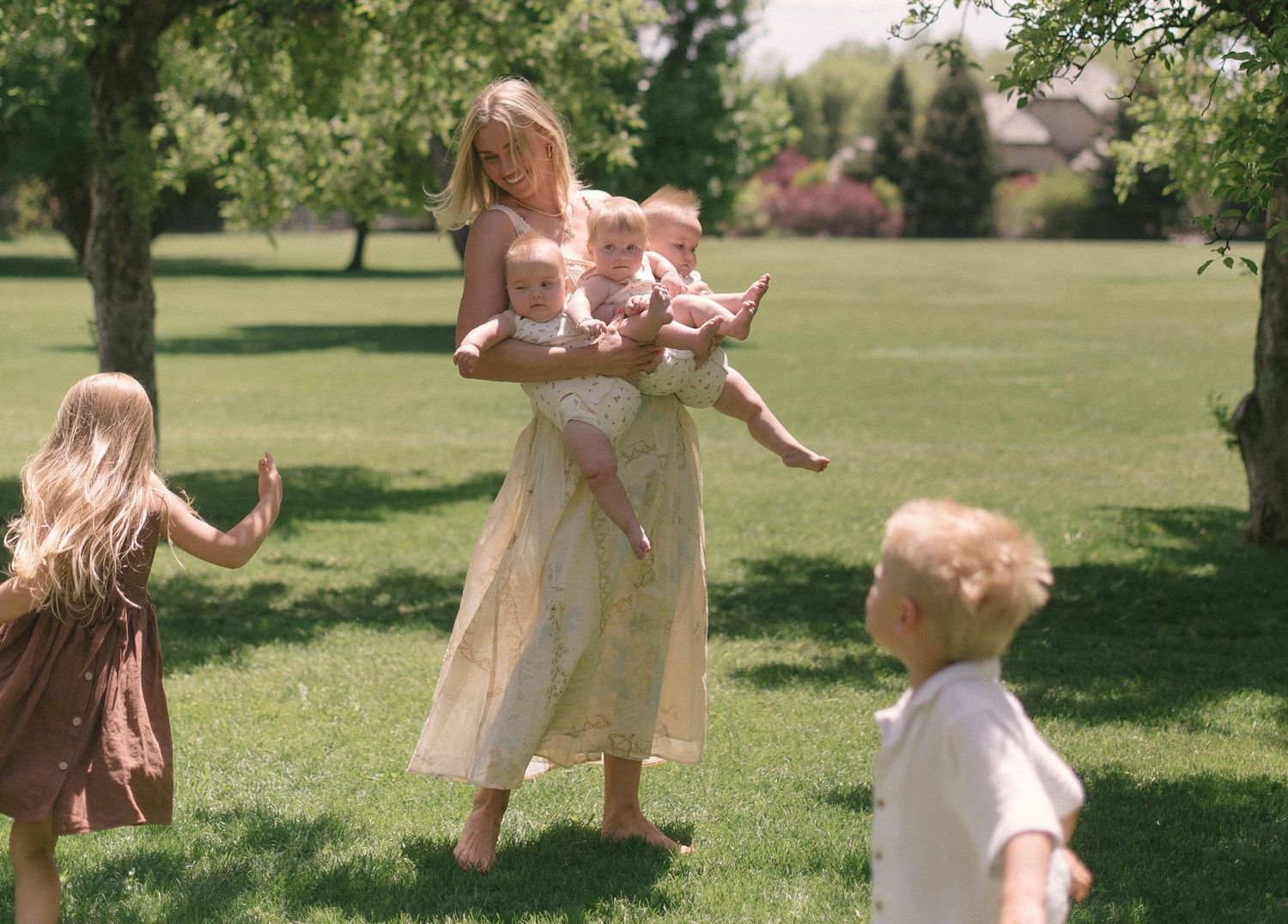 Children and adult playing in a sunny park with pink dresses and natural lighting.