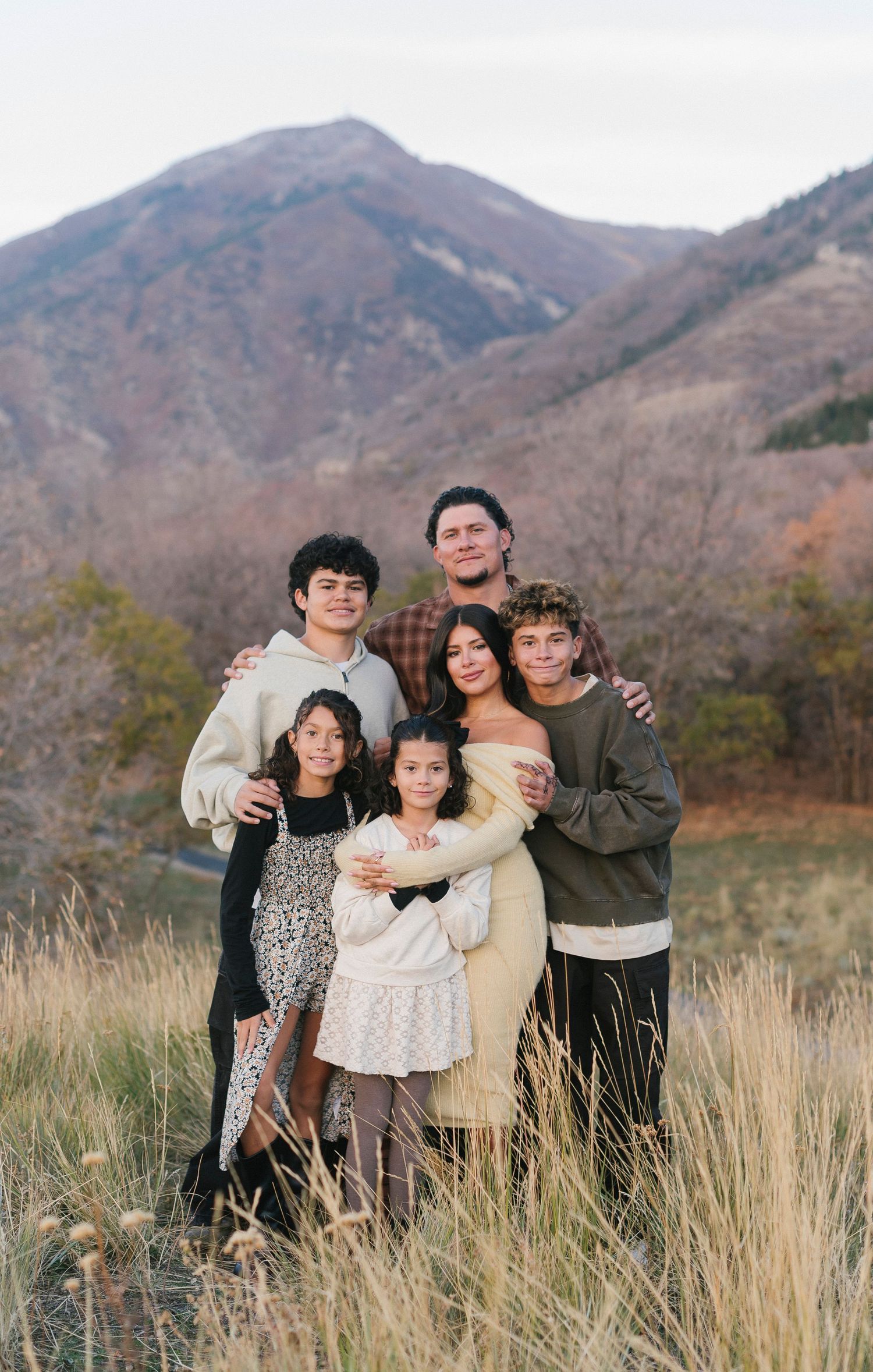 A family portrait taken outdoors against a mountainous backdrop in autumn.