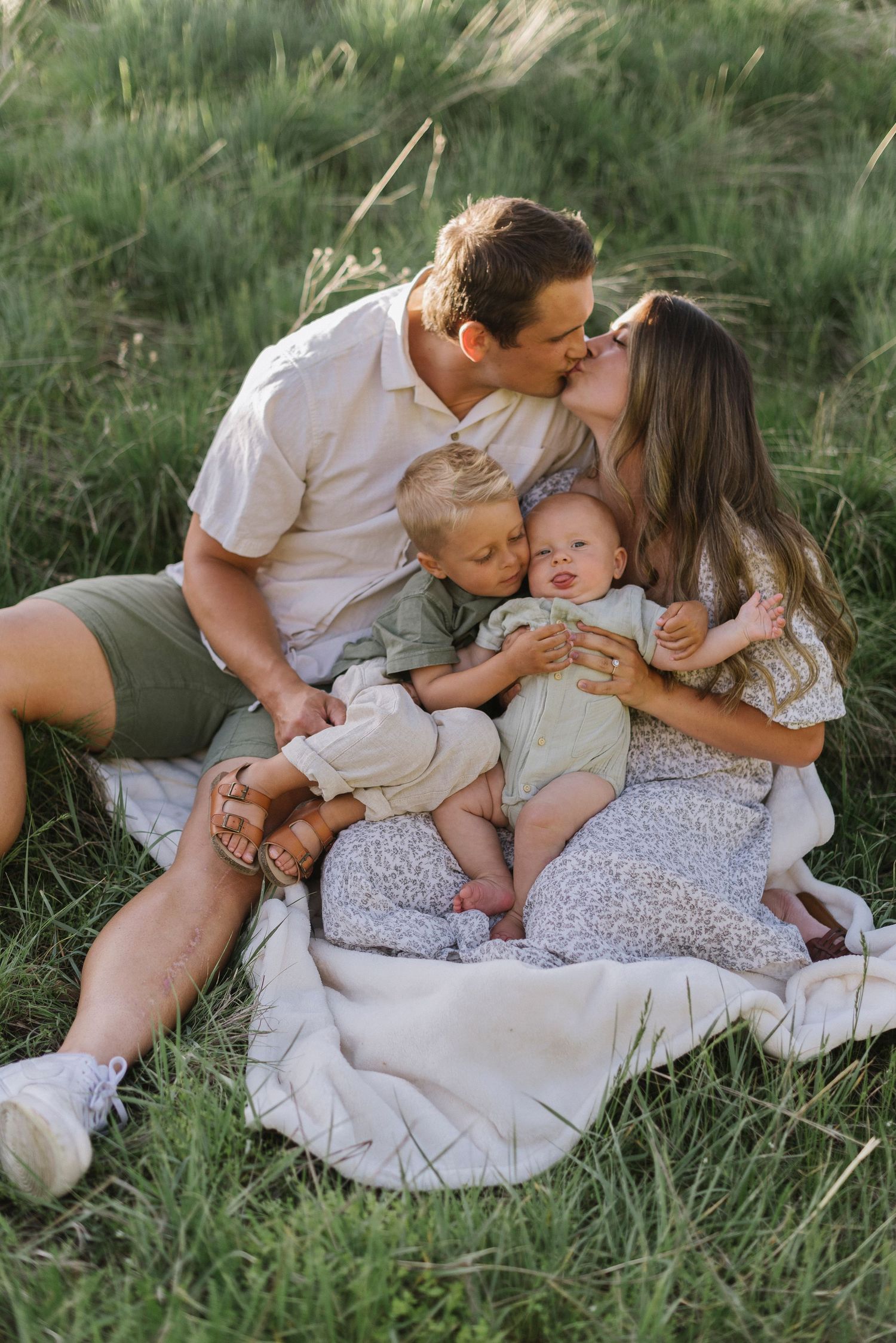 Intimate family portrait session in tall grass showing loving interactions and embraces.