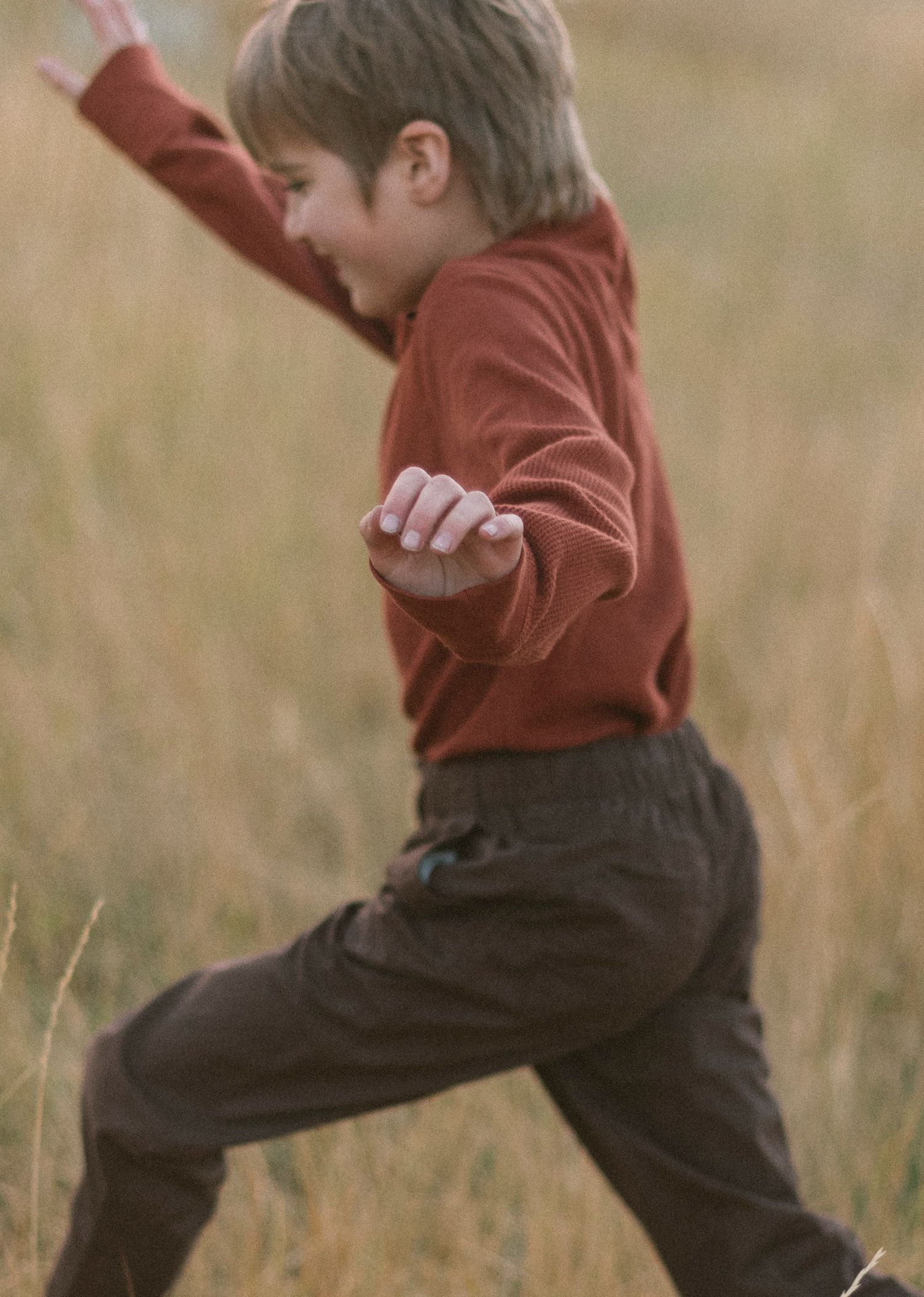 Close-up sequence of legs in brown pants jumping playfully in a grassy field.