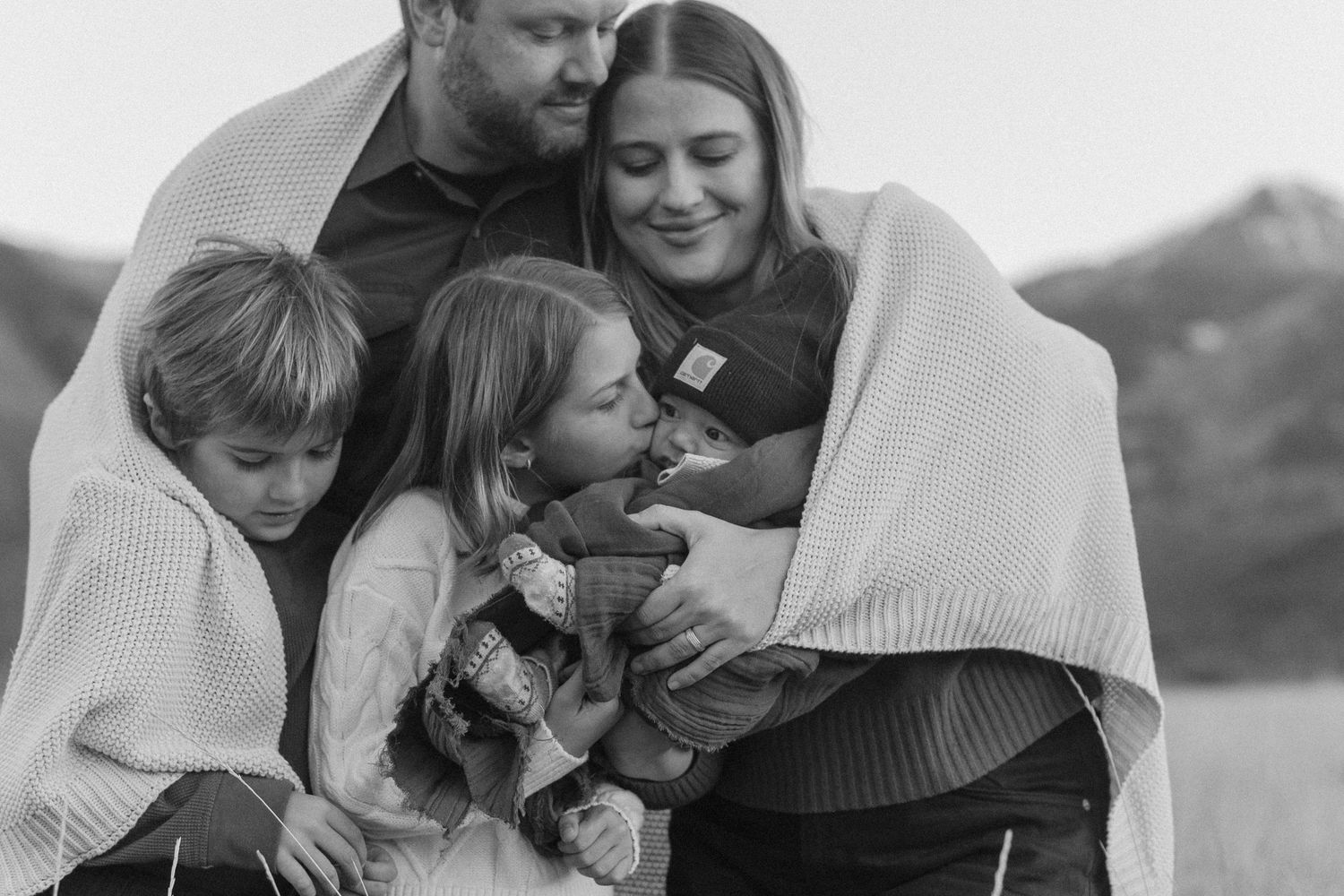 Black and white candid family portrait showing intimate moments outdoors.