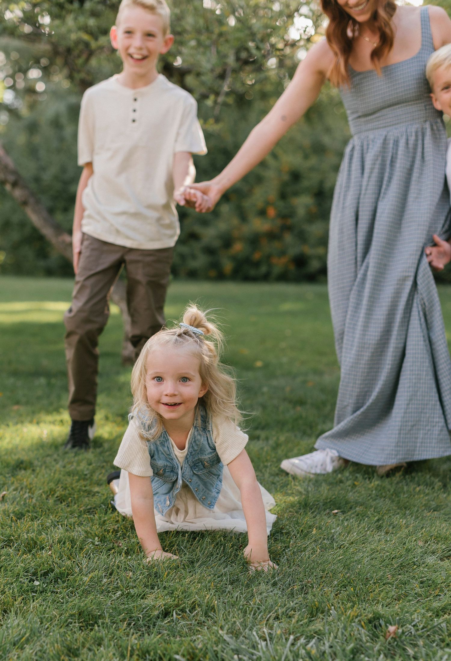 Children playing and crawling on grass while family watches in background.